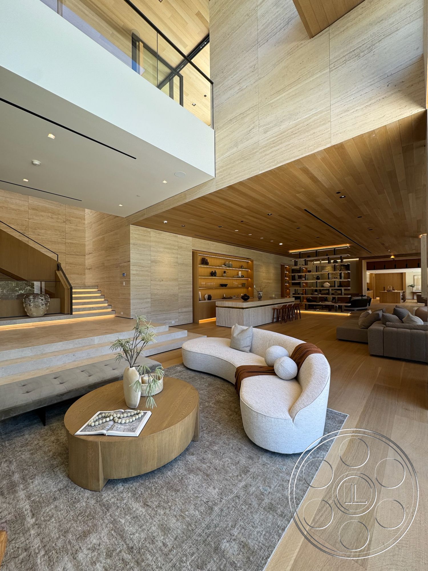 Chalon Estate - minimalist decor, neutral color palette, wood coffee table, light wood flooring, glass railing, soft area rug, textured plaster walls, accent lighting, open layout design, natural wood ceiling panels, floating stairs, built-in wood shelving, rounded sectional sofa