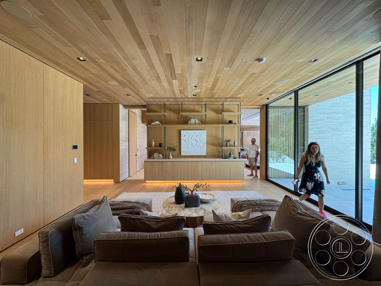 Chalon Estate - neutral color palette, minimalist design elements, decorative wall art, textured throw pillows, open concept living space, seamless indoor-outdoor flow, contemporary coffee table, recessed lighting fixtures, floor-to-ceiling glass windows, upholstered sectional sofa, light wood ceiling planks, light wood paneling walls, modern wood shelving unit