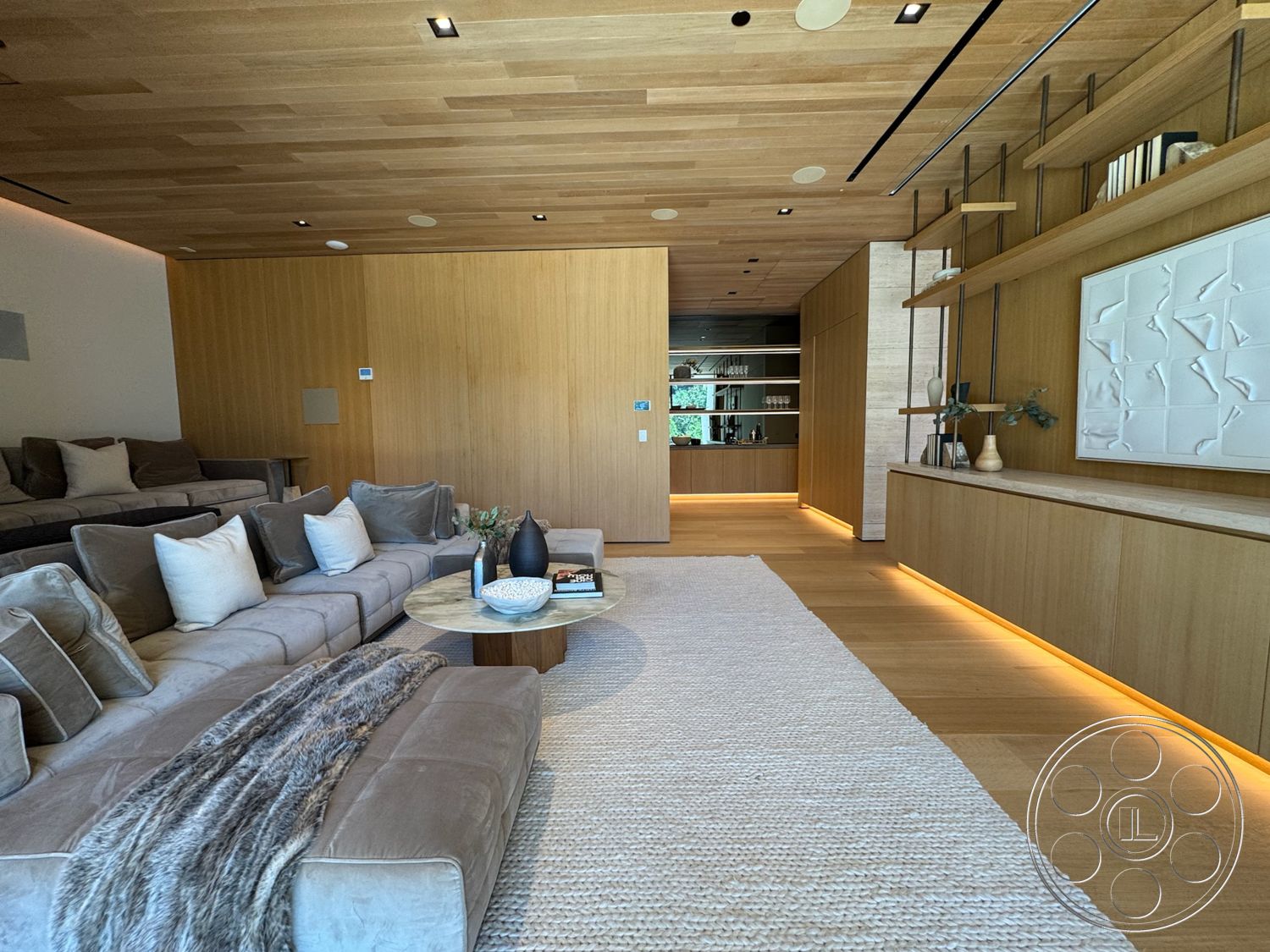 Chalon Estate - neutral color palette, contemporary design, round coffee table, textured area rug, modern furnishings, open living space, light wood paneling, plush fabric sofa, built-in cabinetry, white ceramic vase, ambient LED lighting, hardwood ceiling, decorative wall panel