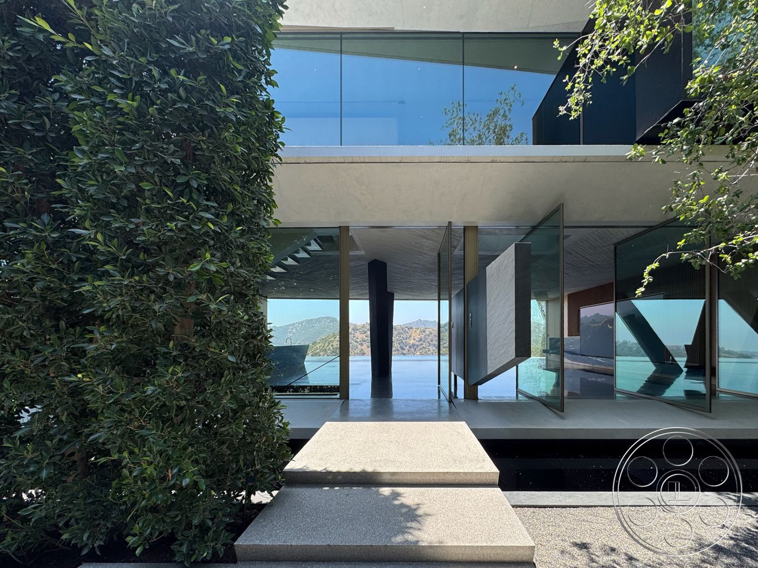 Modern 516 - exterior, minimalist design, large glass windows, glass sliding doors, landscaped greenery, concrete steps, modern architectural style, hillside location, outdoor entrance, steel structural supports, polished concrete patio, rectangular overhang, view of lake