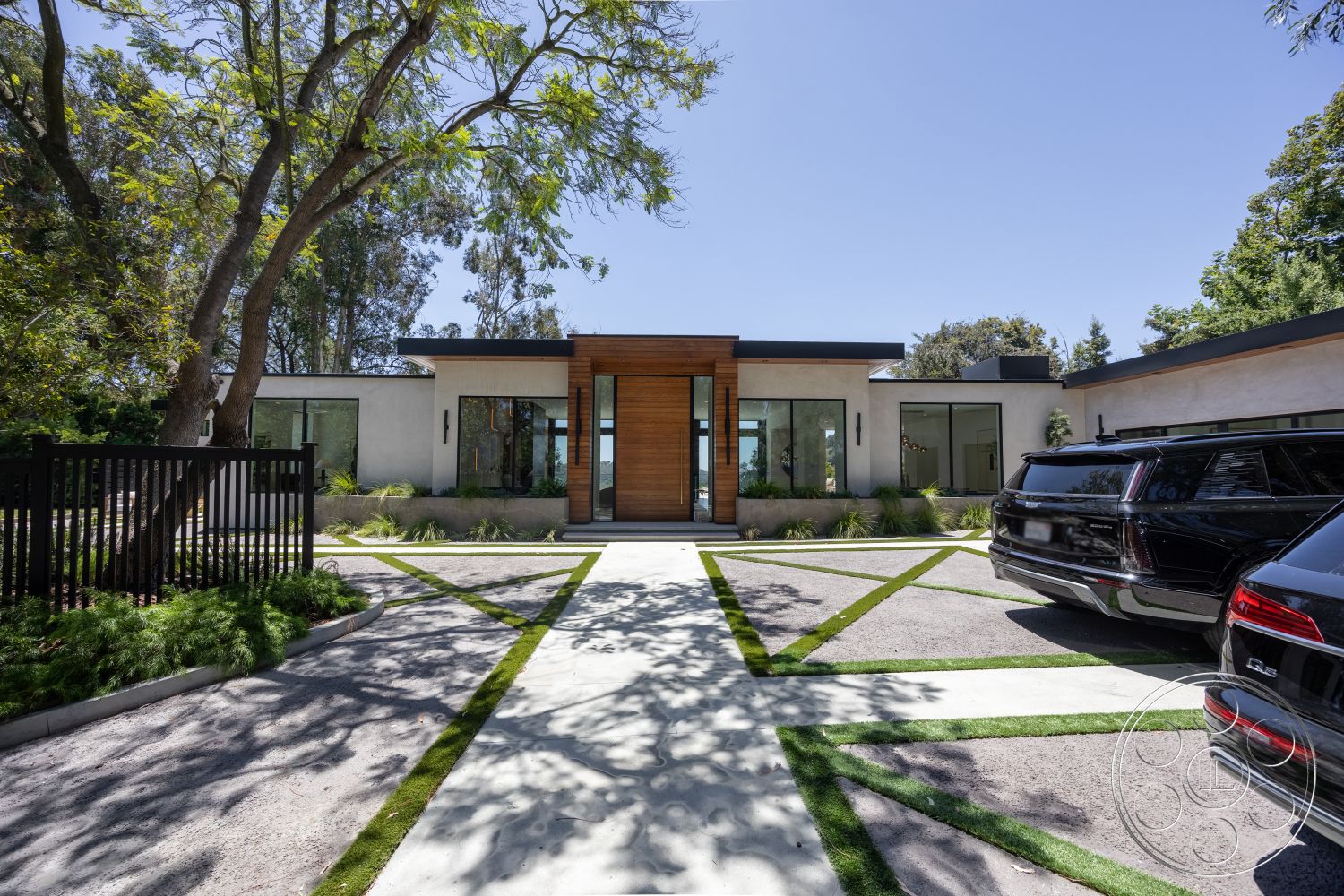 Canyon House - exterior, flat roof, minimalist design, glass windows, landscaped front yard, green lawn, paved walkway, modern architectural style, concrete driveway, stucco walls, black metal fence, wood front door, rectangular driveway, decorative paving strips