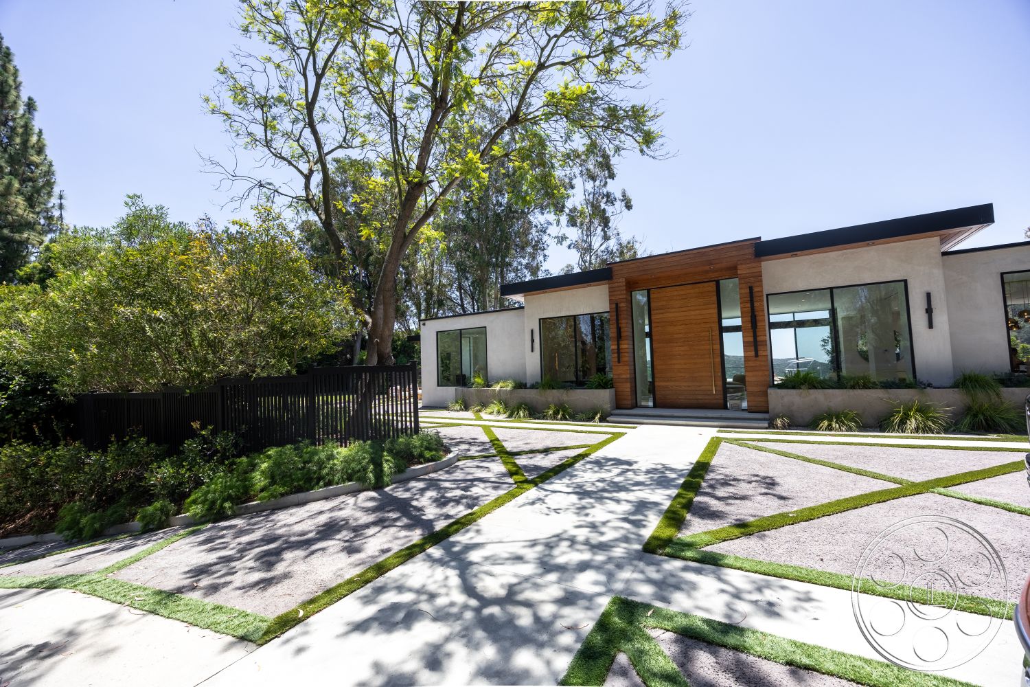 Canyon House - exterior, landscaped garden, flat roof, large glass windows, outdoor greenery, modern architectural style, gravel landscaping, concrete driveway, stucco walls, wood front door, green grass strips, protected from street view