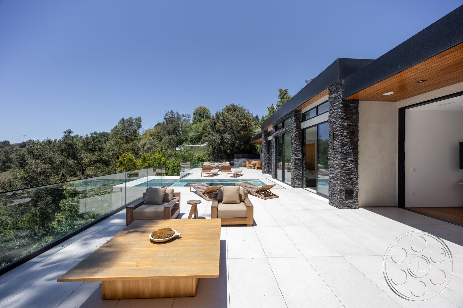 Canyon House - exterior, modern architecture, sliding glass doors, glass railing, rectangular swimming pool, stone feature wall, wooden outdoor furniture, concrete patio flooring, landscaped garden setting, wood beam ceiling, open outdoor living space