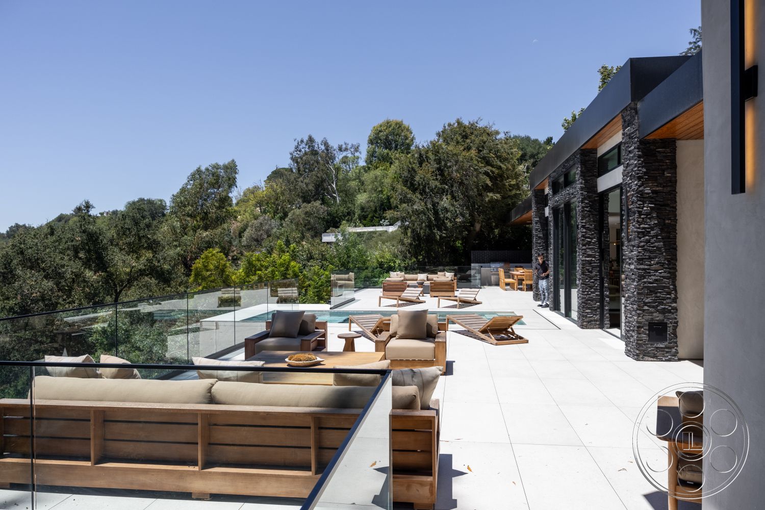 Canyon House - exterior, glass railing, modern outdoor furniture, rectangular swimming pool, stone feature wall, concrete patio flooring, wood beam ceiling, natural landscape setting, open-air patio area, wood deck chairs