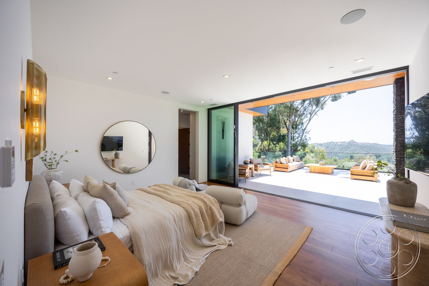 Canyon House - outdoor seating area, mountain view, exposed ceiling beams, hardwood bedroom floors, white painted walls, floor-to-ceiling glass sliding doors, round wall mirror, light beige knitted throw blanket, modern wooden bed frame