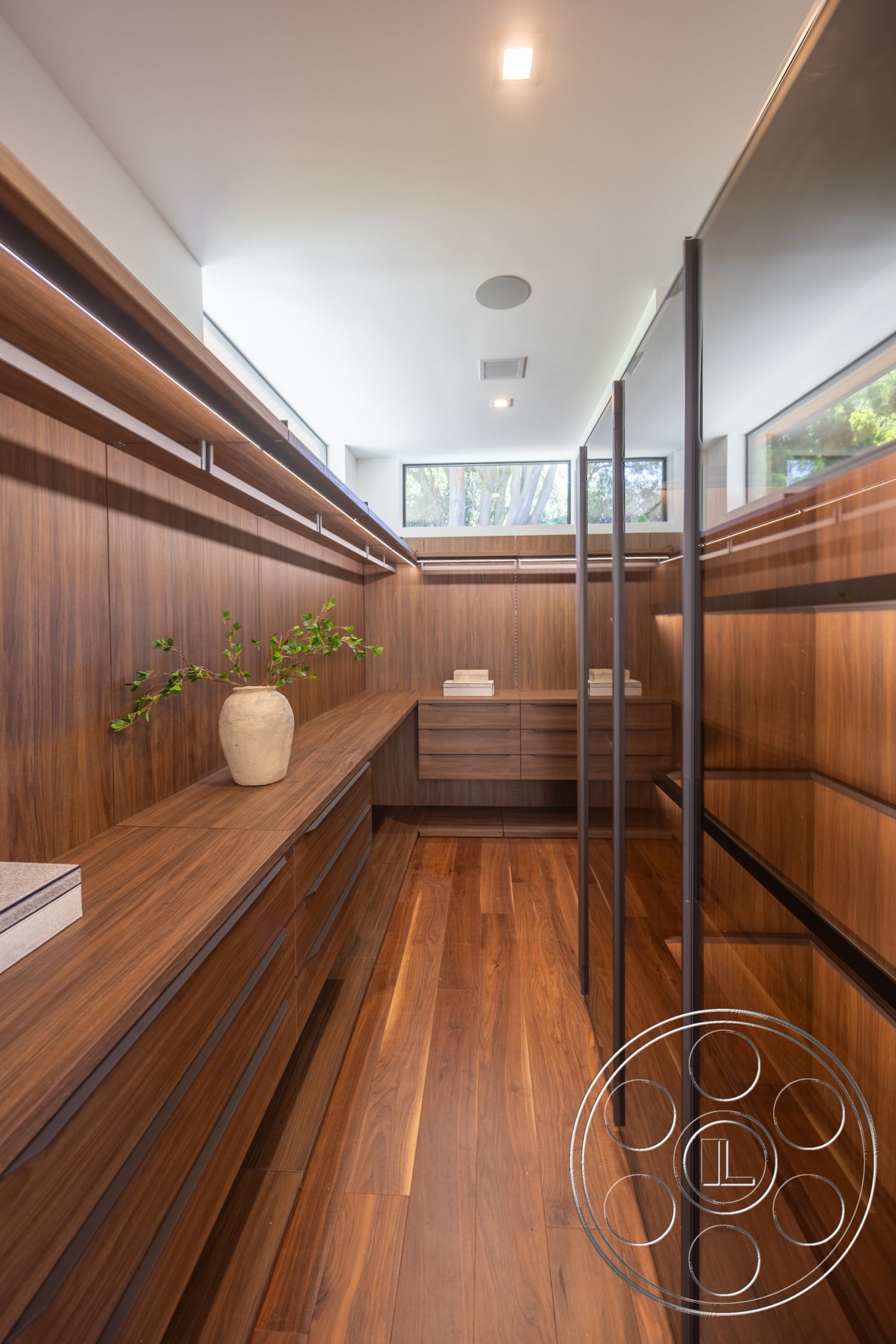Canyon House - hardwood flooring, bright natural light, walnut cabinetry, recessed ceiling lights, linear layout, minimalist closet design, floating walnut shelves, glass closet doors, modern storage solutions