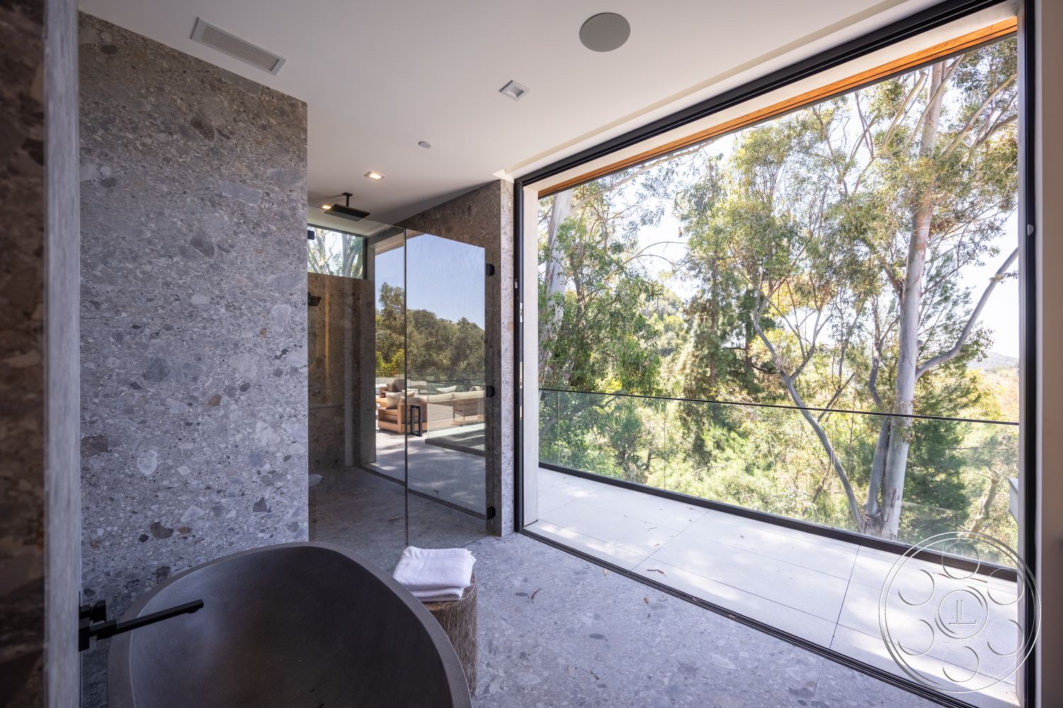 Canyon House - minimalist aesthetic, nature view, sliding glass doors, smooth concrete flooring, glass shower doors, modern bathroom design, wood trim details, exposed aggregate stone walls, freestanding stone bathtub, large windows with balcony access