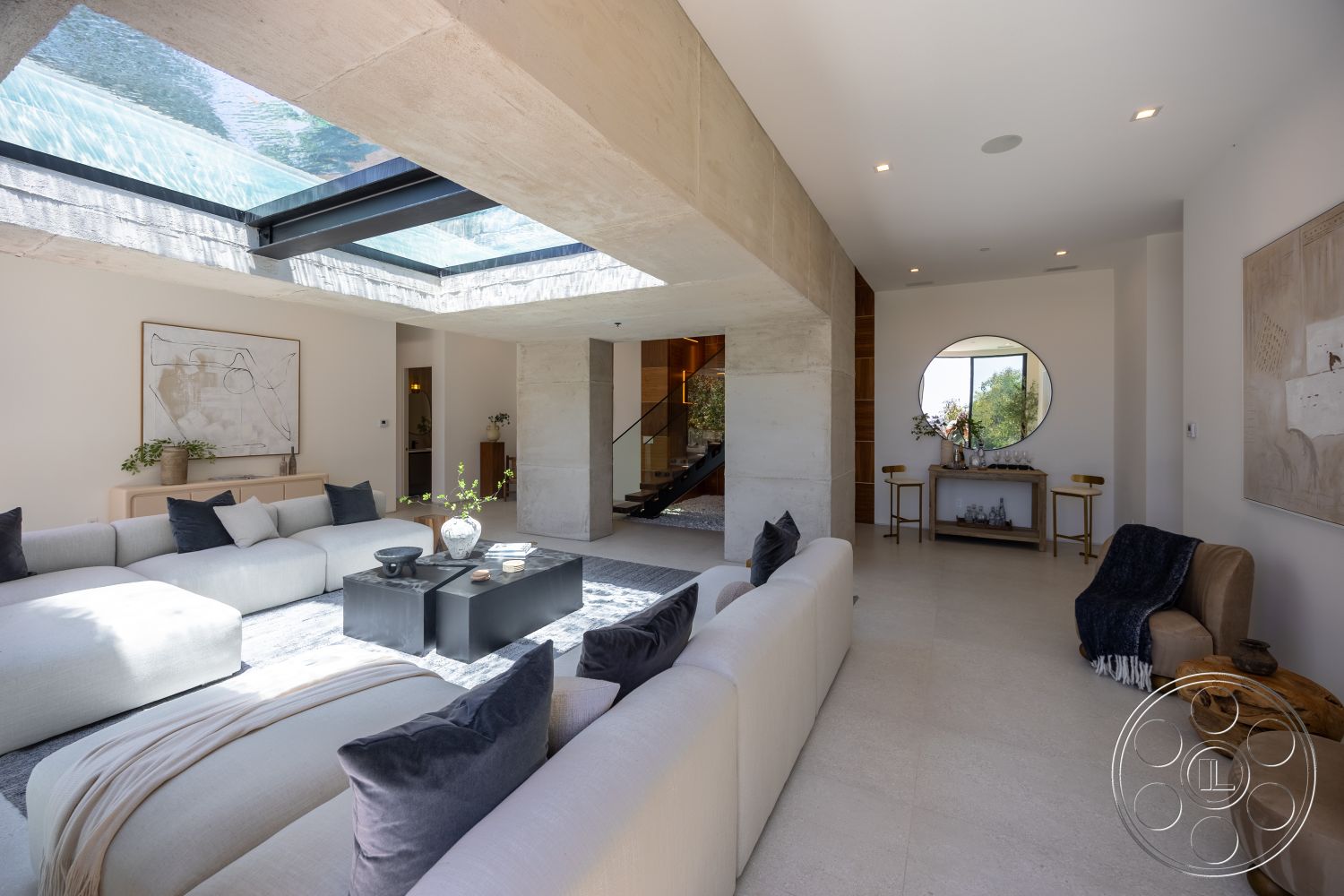 Canyon House - minimalist decor, neutral color palette, textured wall art, concrete walls, floor-to-ceiling windows, exposed ceiling, black coffee table, wooden side table, glass skylight, modern sectional sofa, decorative accent pillows, architectural lighting fixtures, slate floor tiles, open living area, curved window
