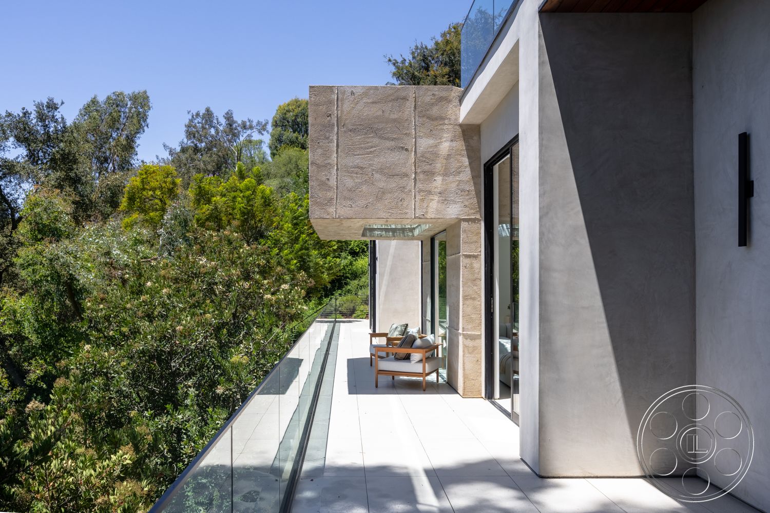 Canyon House - exterior, outdoor seating area, concrete patio flooring, floor-to-ceiling glass windows, metal railing balcony, concrete facade panels, stone-like texture surface, large overhanging roof, landscaped greenery surrounding