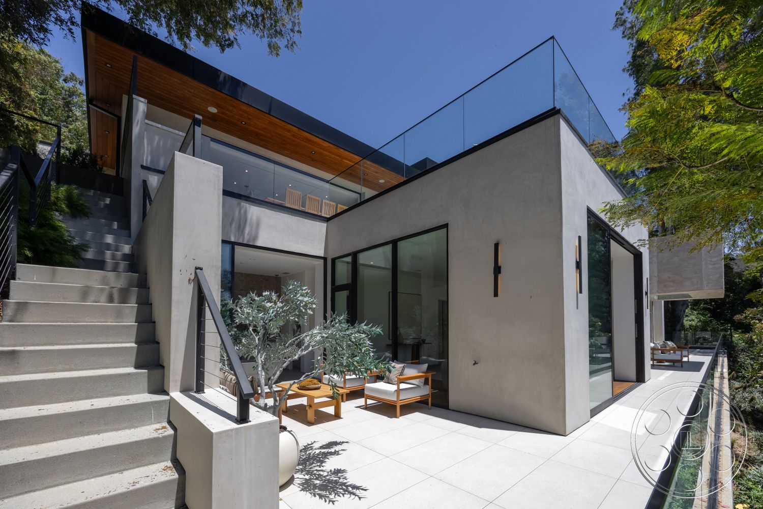 Canyon House - exterior, landscaped surroundings, modern outdoor furniture, metal railing, concrete steps, rectangular patio area, floor-to-ceiling glass windows, glass balcony railing, polished concrete walls, wood ceiling slats