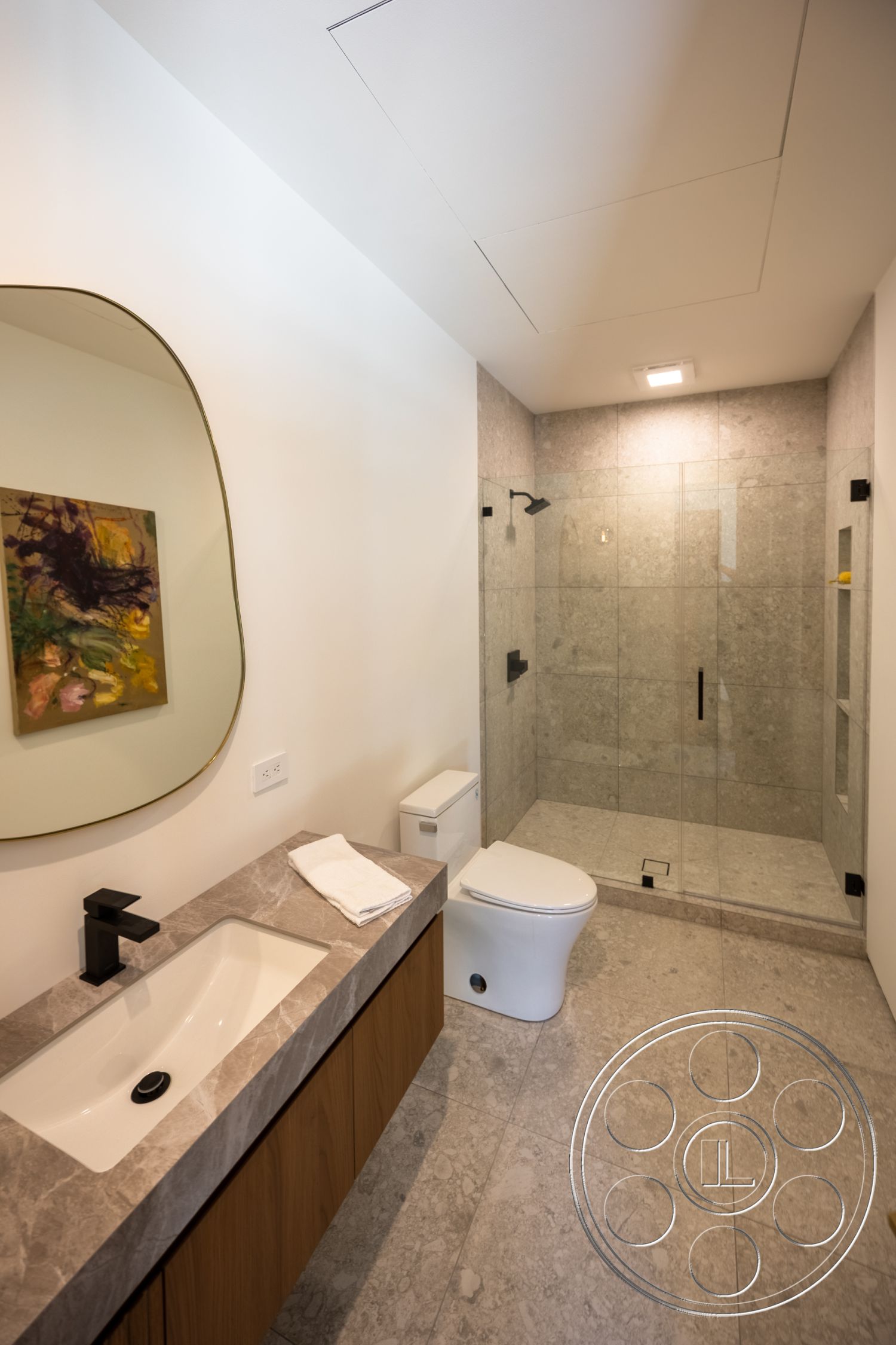 Canyon House - framed wall art, textured plaster walls, wall-mounted faucet, glass shower doors, recessed ceiling lighting, marble bathroom flooring, marble vanity countertop, modern toilet, wood bathroom cabinetry, black shower fixtures, large format tile walls