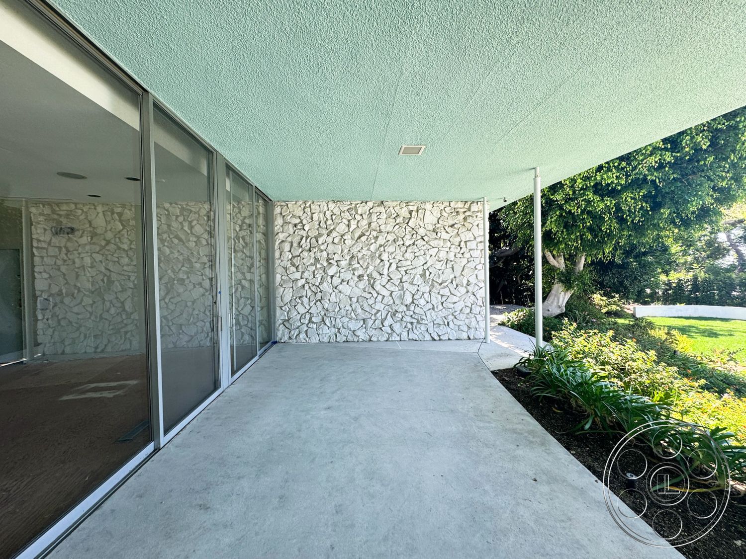 MCM 28 - exterior, sliding glass doors, green landscaping, modern architectural style, textured plaster ceiling, stone feature wall, concrete patio flooring