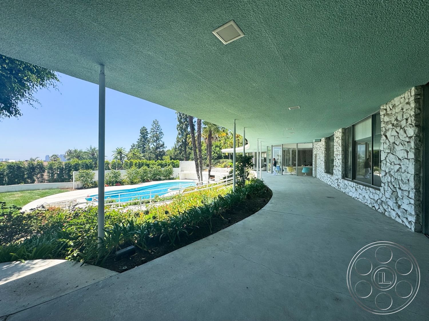 MCM 28 - exterior, glass sliding doors, metal railings, rectangular swimming pool, modern architectural style, concrete walkway, tropical vegetation, poolside seating area, stone feature wall, paved pool deck, landscaped garden area, aluminum window frames, curved patio, overhead textured ceiling