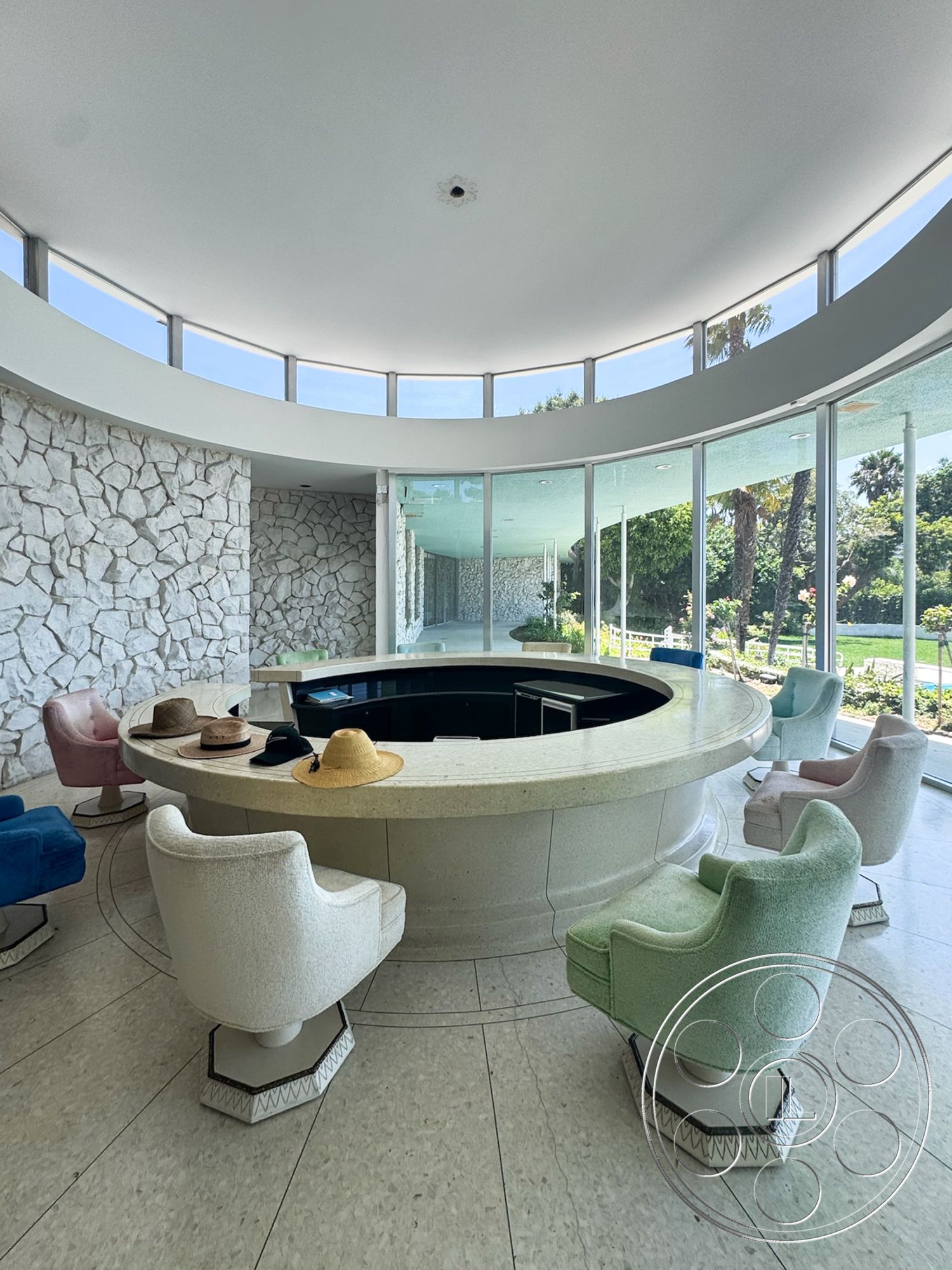 MCM 28 - natural light, contemporary style, textured flooring, stone accent wall, open layout, modern design, large glass windows, curved bar countertop, surrounding garden view, colorful upholstered chairs, circular ceiling