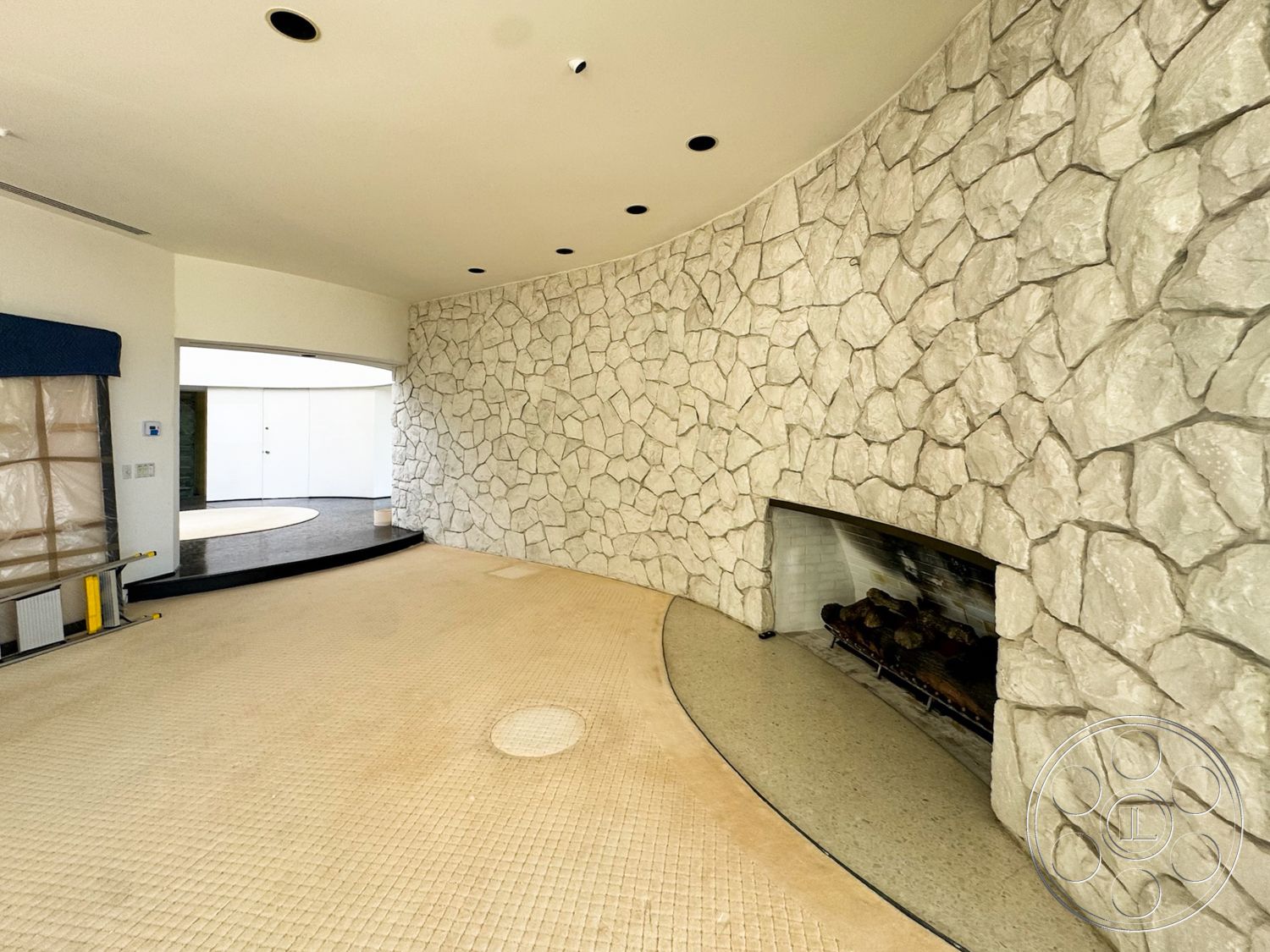 MCM 28 - neutral color palette, open floor plan, curved wall design, floor-to-ceiling window, modern architectural details, textured stone fireplace wall, creamy tile flooring, exposed stone surface