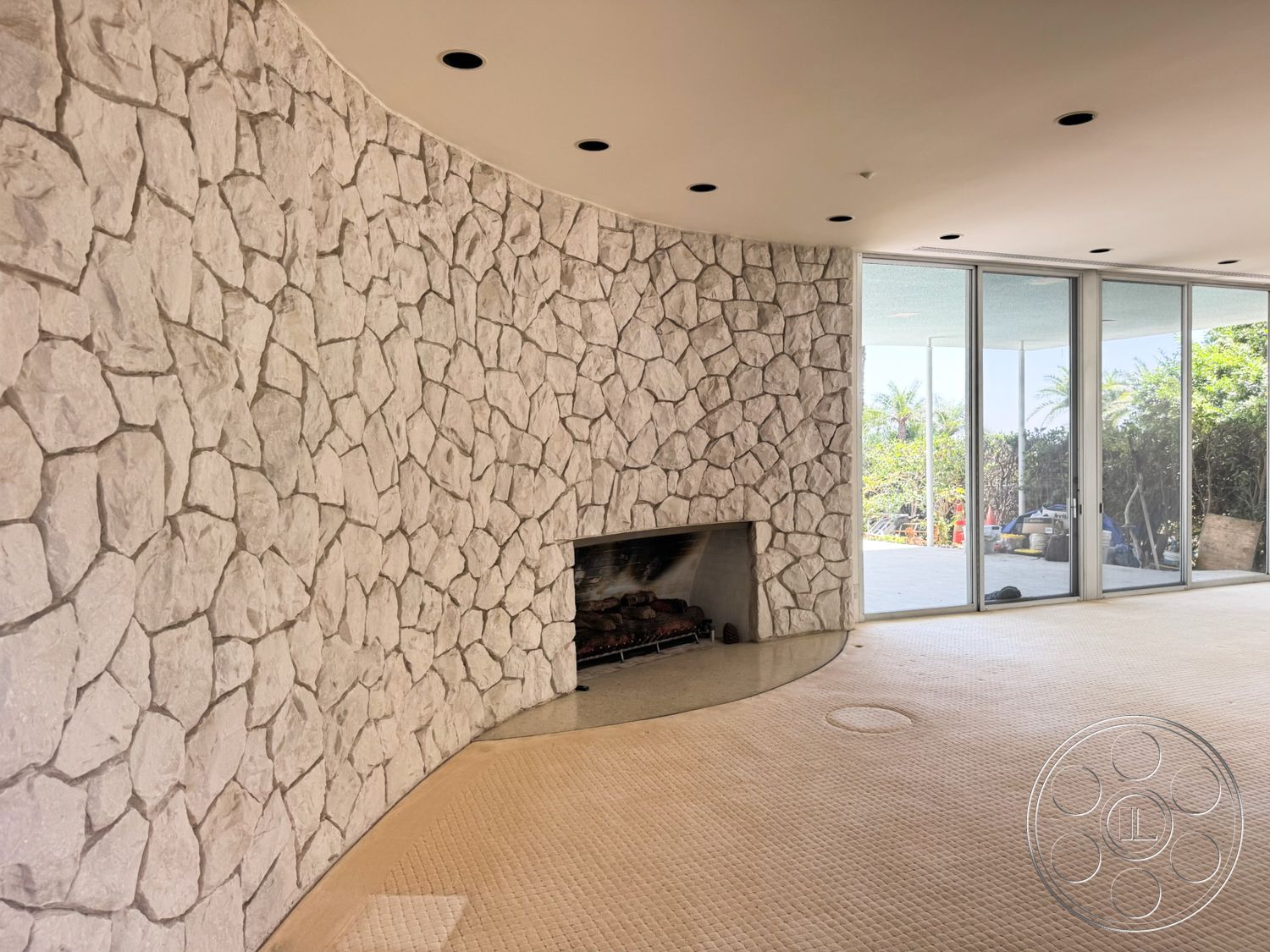 MCM 28 - natural light, open concept layout, floor-to-ceiling windows, carpet flooring, minimalistic design, stone feature wall, rounded stone fireplace surround, light-colored stone veneer, curved wall detail
