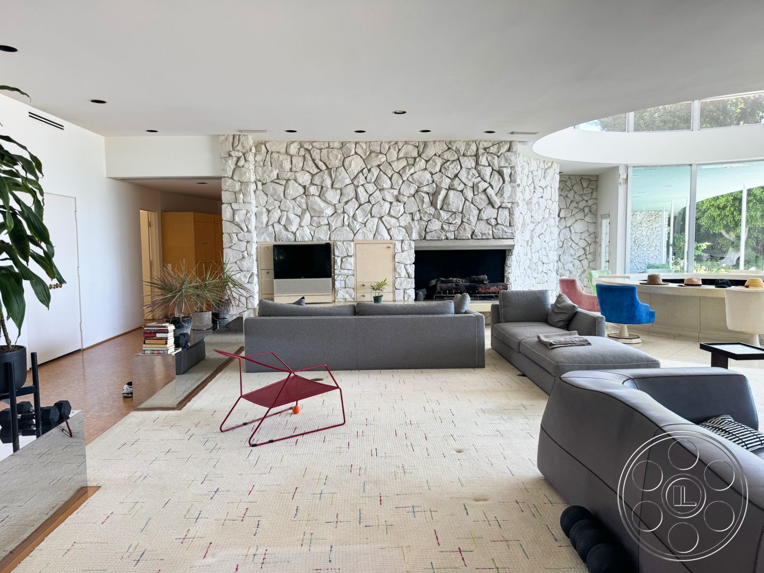 MCM 28 - neutral color palette, natural light, decorative area rug, open floor plan, light wood flooring, minimalist furniture, curved ceiling, contemporary coffee table, exposed stone wall, modern art decor, modern sectional sofa, translucent glass windows, plant in modern planter, boxy architectural forms