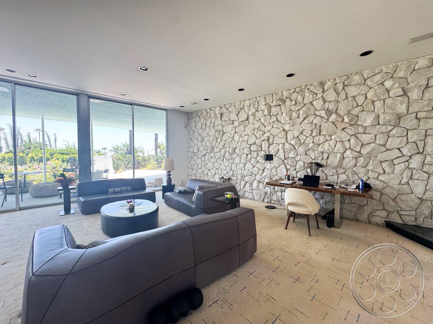 MCM 28 - contemporary design, natural lighting, round coffee table, open floor plan, modern furniture, floor-to-ceiling windows, soft area rug, leather sofa, wood desk, exposed stone feature wall, elegant desk lamp