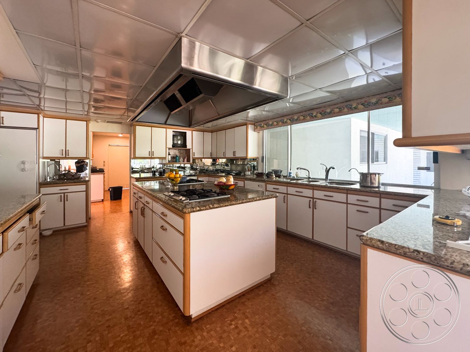 MCM 28 - stainless steel kitchen appliances, open kitchen layout, granite kitchen countertops, drop ceiling tiles, kitchen island with seating, white painted kitchen walls, large kitchen windows, laminate kitchen cabinetry, wood laminate kitchen flooring