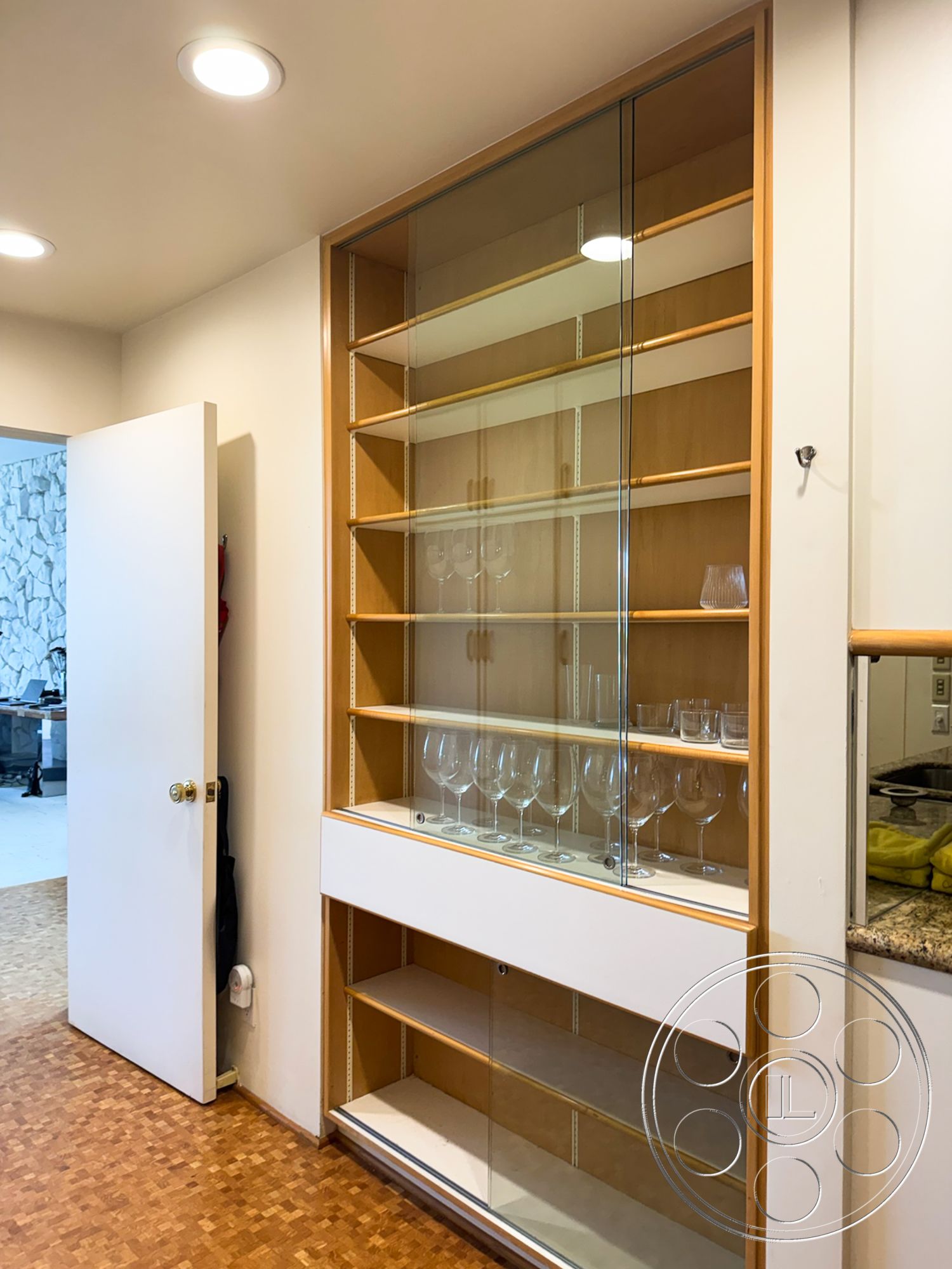 MCM 28 - wood cabinetry, minimalist design elements, granite countertop, cork flooring, built-in cabinetry, modern kitchen design, white painted walls, glass display shelves, shelving with glass doors, open shelving for glassware