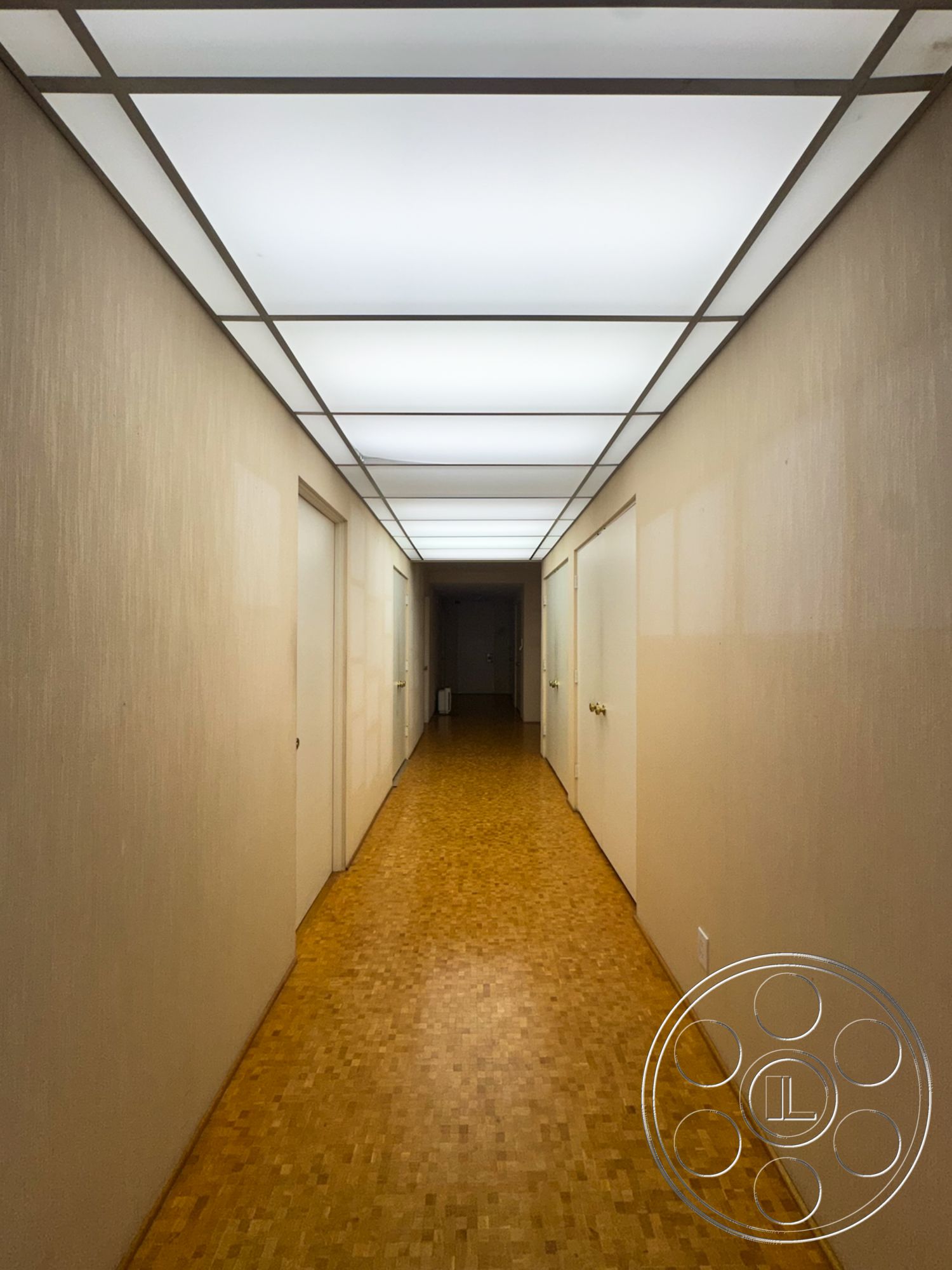 MCM 28 - minimalist design, light wood flooring, textured plaster walls, interior hallway, white painted doors, linear recessed ceiling lighting, gold handle details