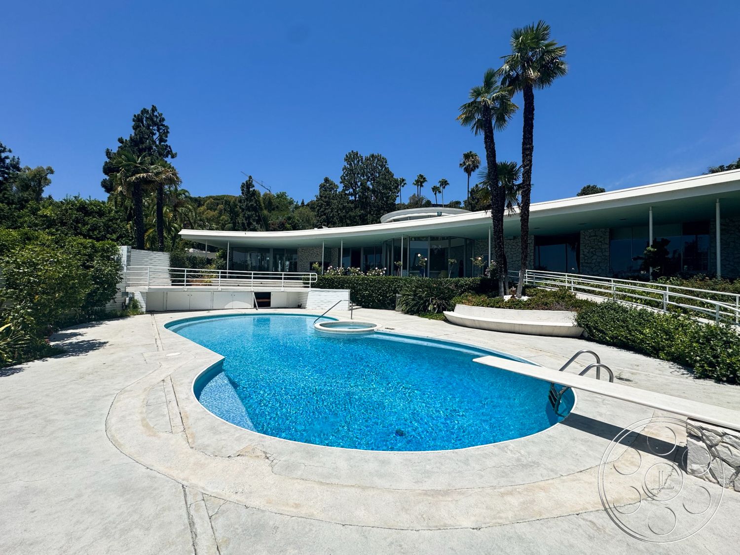 MCM 28 - exterior, glass windows, modern architectural style, desert landscape, concrete pool deck, textured concrete surface, surrounding palm trees, oval pool, landscaped garden area, curved patio