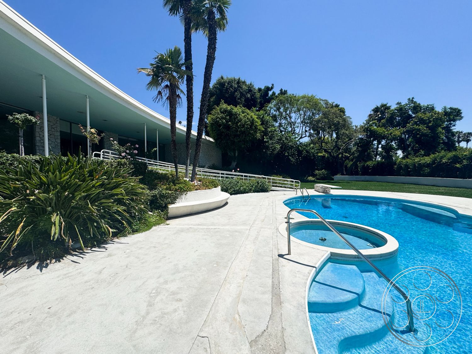 MCM 28 - exterior, palm trees, concrete pathway, glass windows, circular hot tub, lawn area, white railing, concrete pool deck, rectangular pool, mid-century modern architecture, stucco exterior walls, landscaped garden with tropical plants