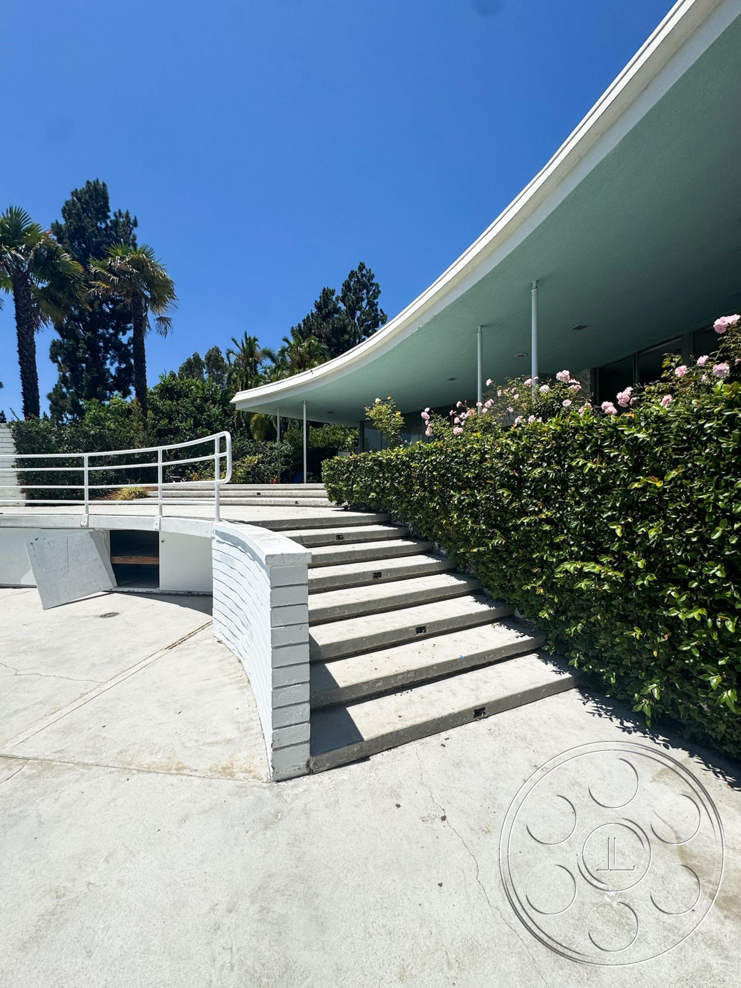 MCM 28 - exterior, landscaped garden, modern architectural style, concrete patio floor, concrete stair treads, curved entry stairs, white painted brick railing, palm tree setting
