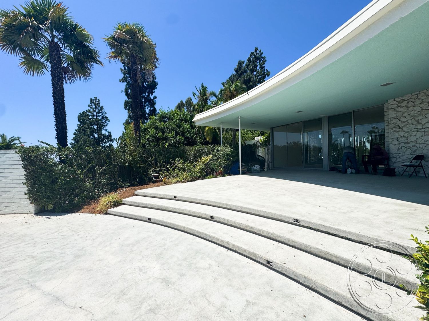 MCM 28 - exterior, flat roof, glass sliding doors, raised garden beds, stone feature wall, concrete patio flooring, palm tree landscaping, curved concrete steps, horizontal wood slat fence