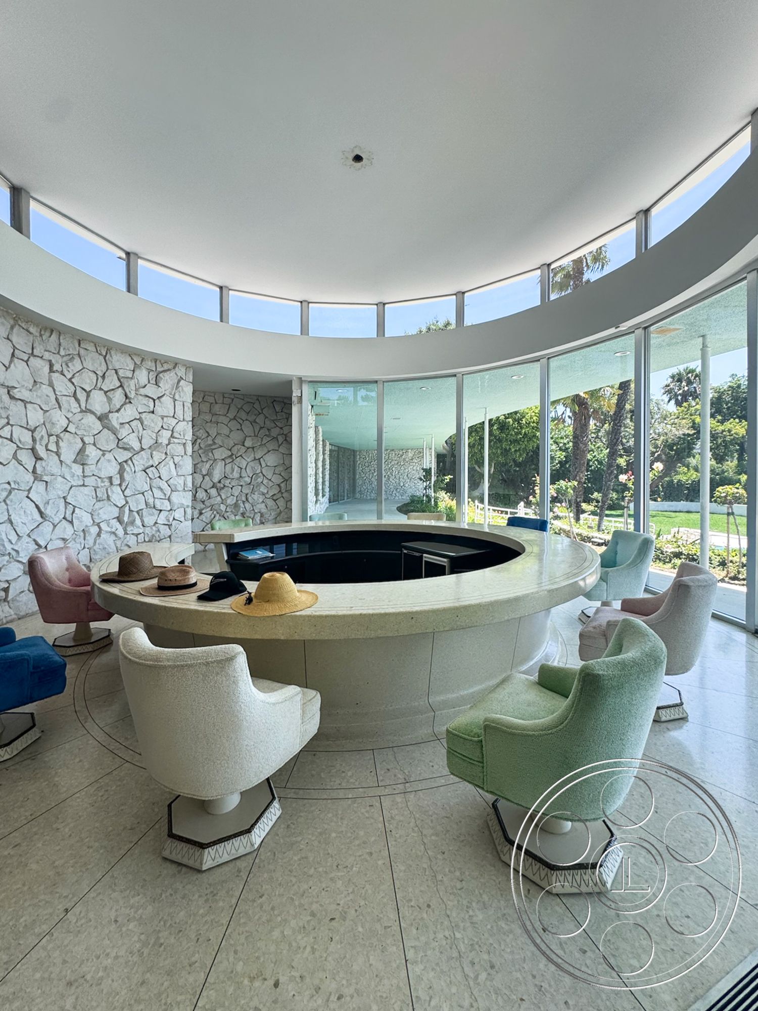 MCM 28 - circular seating arrangement, modernist design elements, contemporary architectural style, glass floor-to-ceiling windows, round stone feature wall, white polished concrete floor, curved stone bar countertop, soft upholstered armchairs