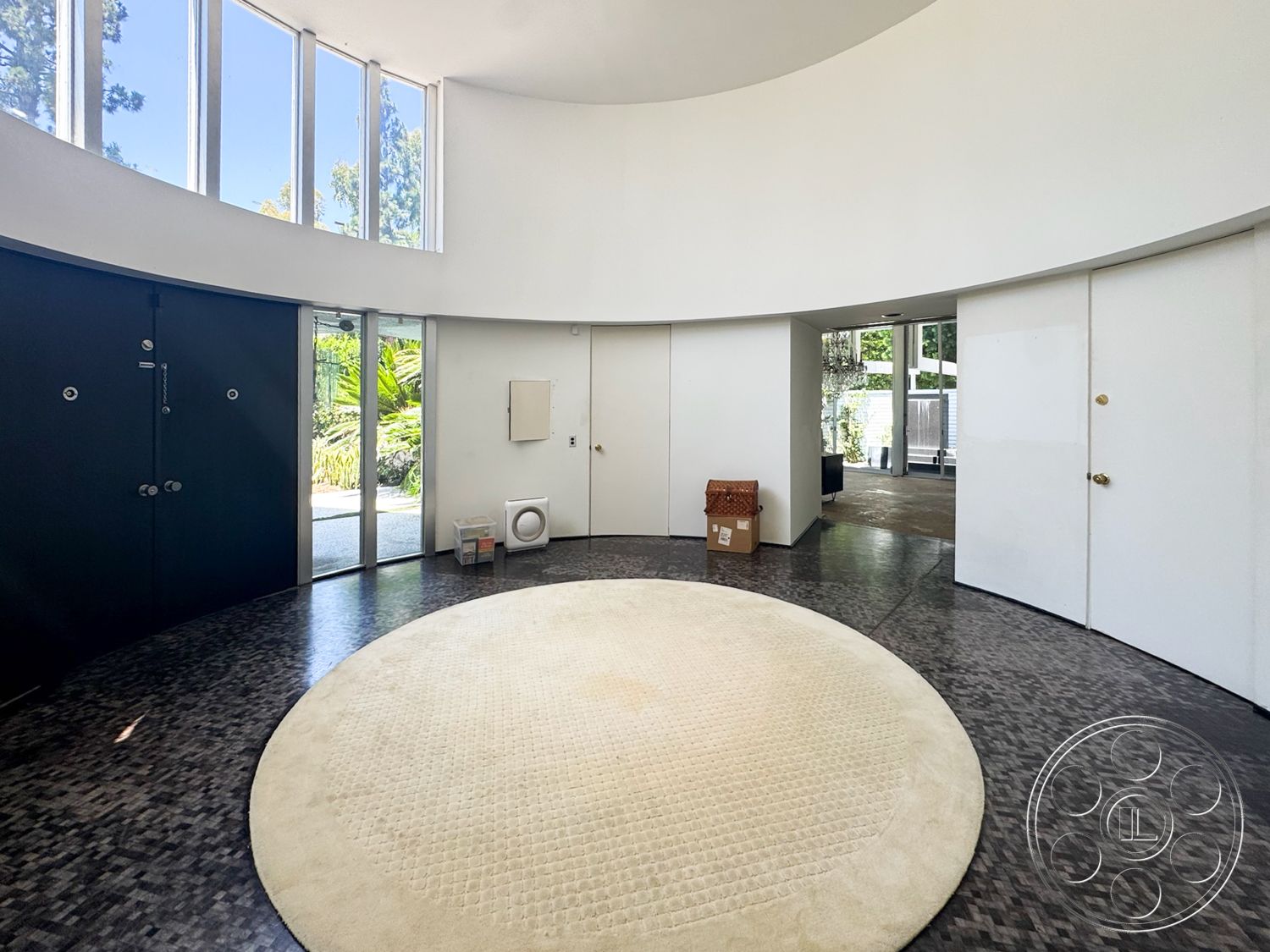 MCM 28 - minimalist design, open floor plan, polished concrete flooring, floor-to-ceiling windows, bright natural lighting, modern architectural style, curved wall design, dark wood accent wall, round area rug