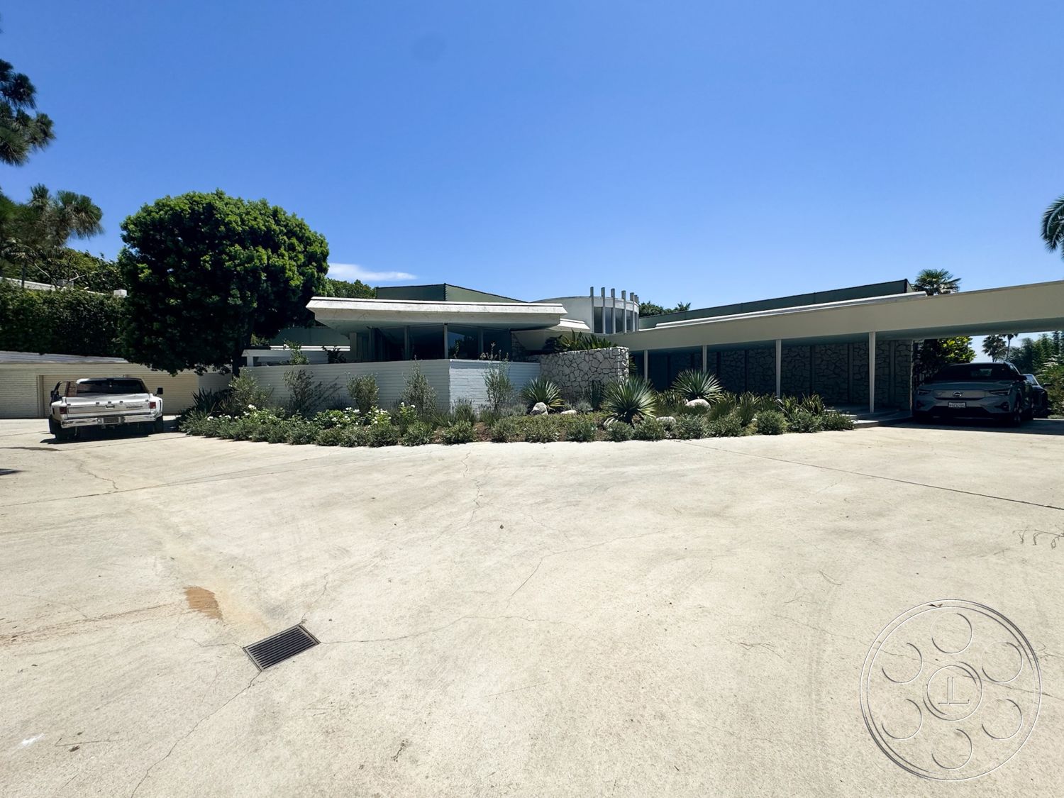 MCM 28 - exterior, minimalist design, floor-to-ceiling windows, vaulted ceiling, modern architectural style, concrete driveway, horizontal wood paneling, succulent plants, flat roof design, landscaped garden beds, stone garden wall, carport structure, curved landscape