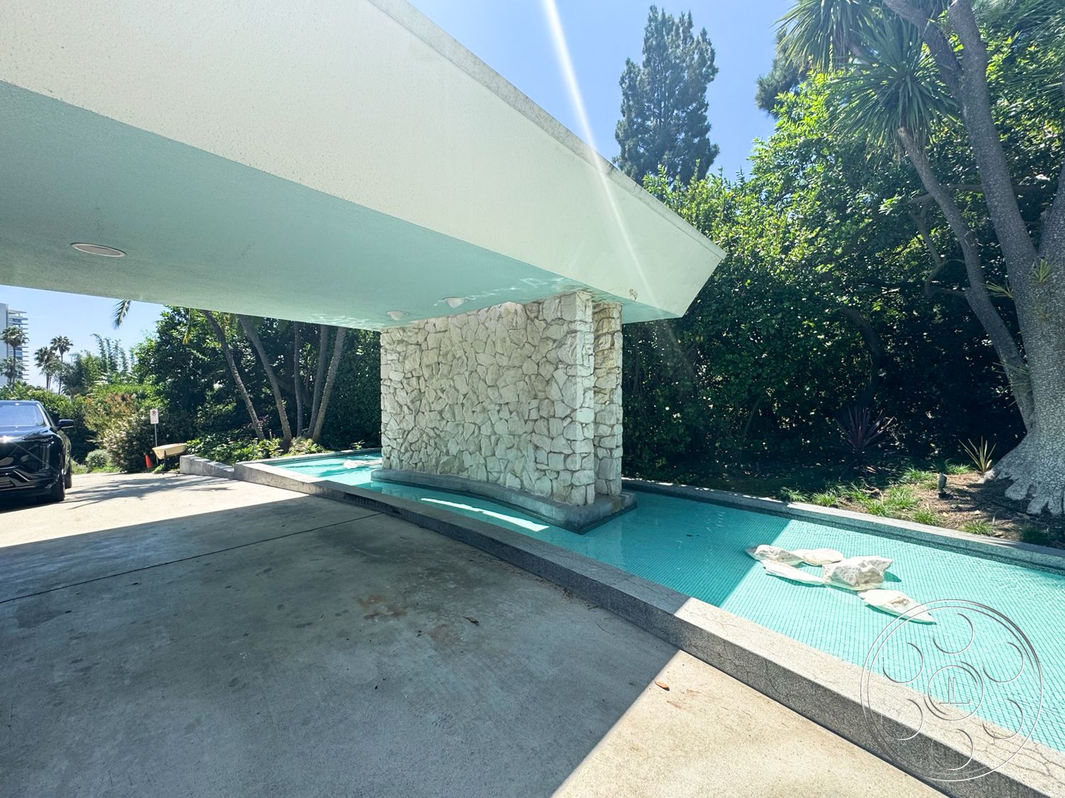 MCM 28 - exterior, concrete driveway, tropical palm trees, landscaped garden area, flat roof structure, multi-level outdoor space, stone water feature wall, glass tile pool border