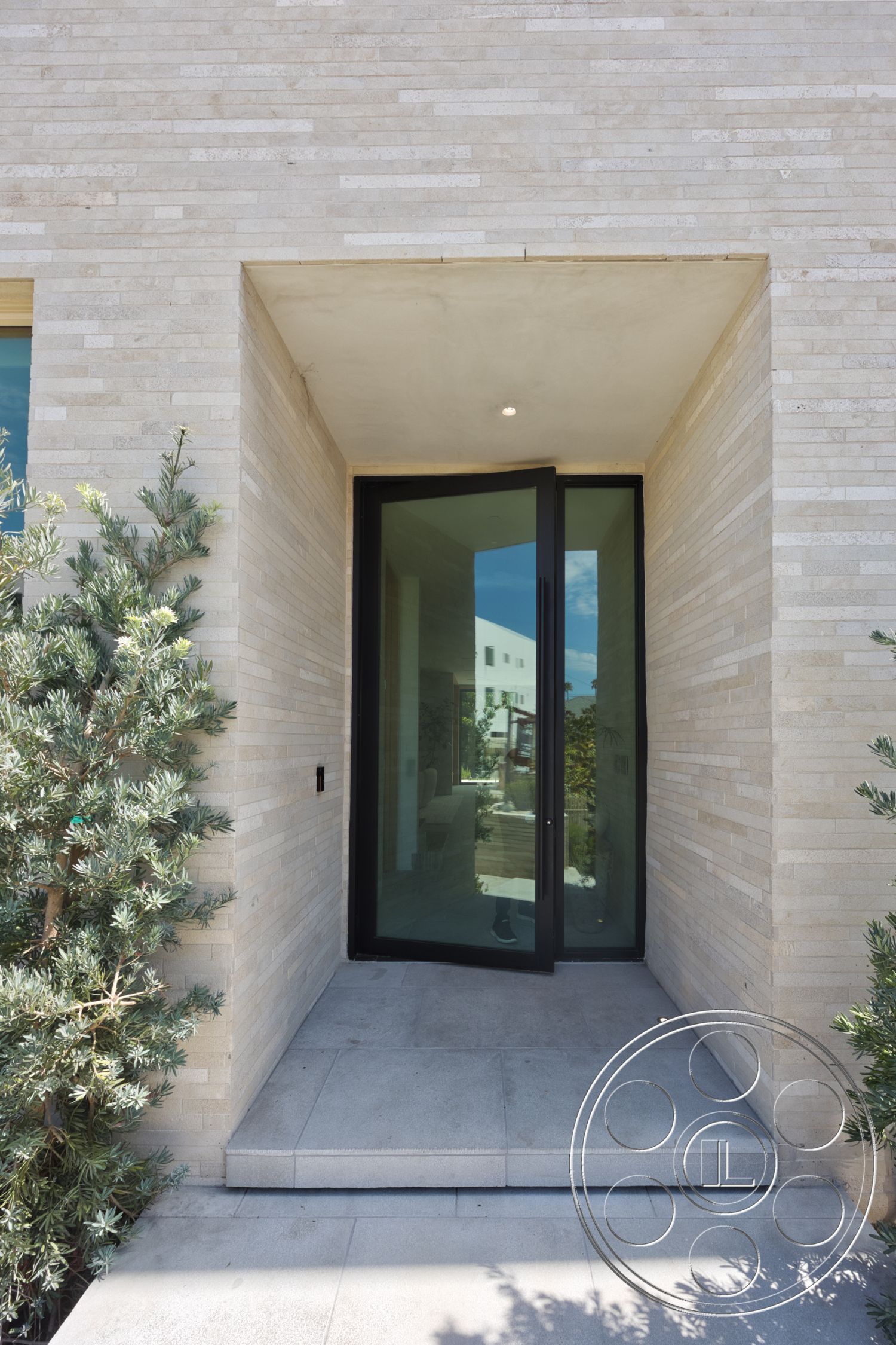 Modern 526 - neutral color palette, exterior, landscaped greenery, textured stone facade, minimalist architectural style, floor-to-ceiling glass panels, concrete entry steps, large glass entry door, rectangular entryway, overhang roof detail