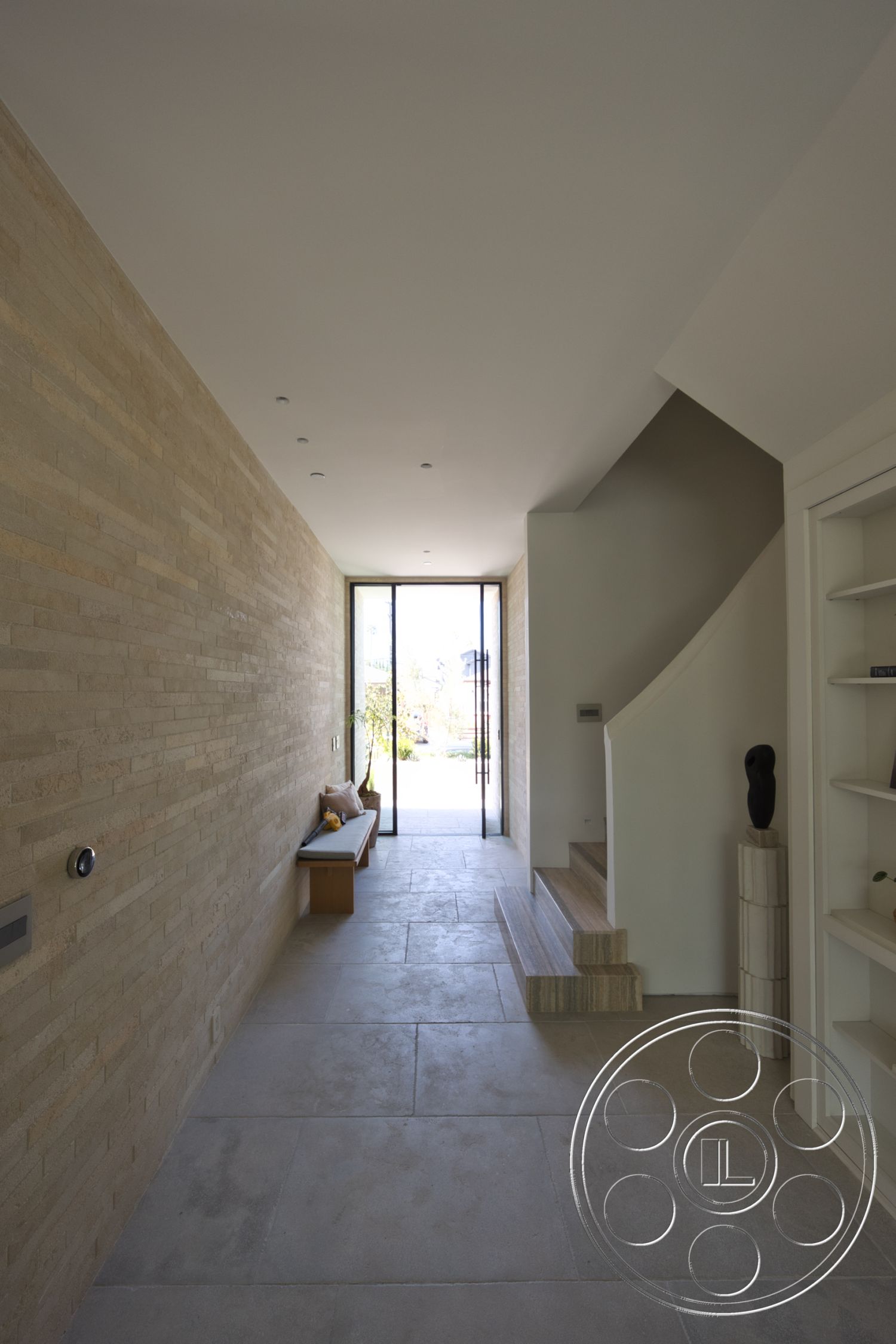 Modern 526 - neutral color palette, natural light, minimalist design, open floor plan, built-in shelving, stone flooring, concrete steps, modern architectural style, wooden bench seating, curved staircase, interior hallway, exposed brick accent wall, large glass entrance door