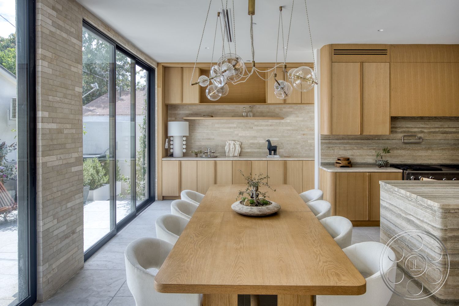 Modern 526 - open concept layout, modern pendant lighting, large glass windows, ceramic tile flooring, light wood cabinetry, light wood dining table, textured stone accent wall, white upholstered dining chairs, natural stone backsplash