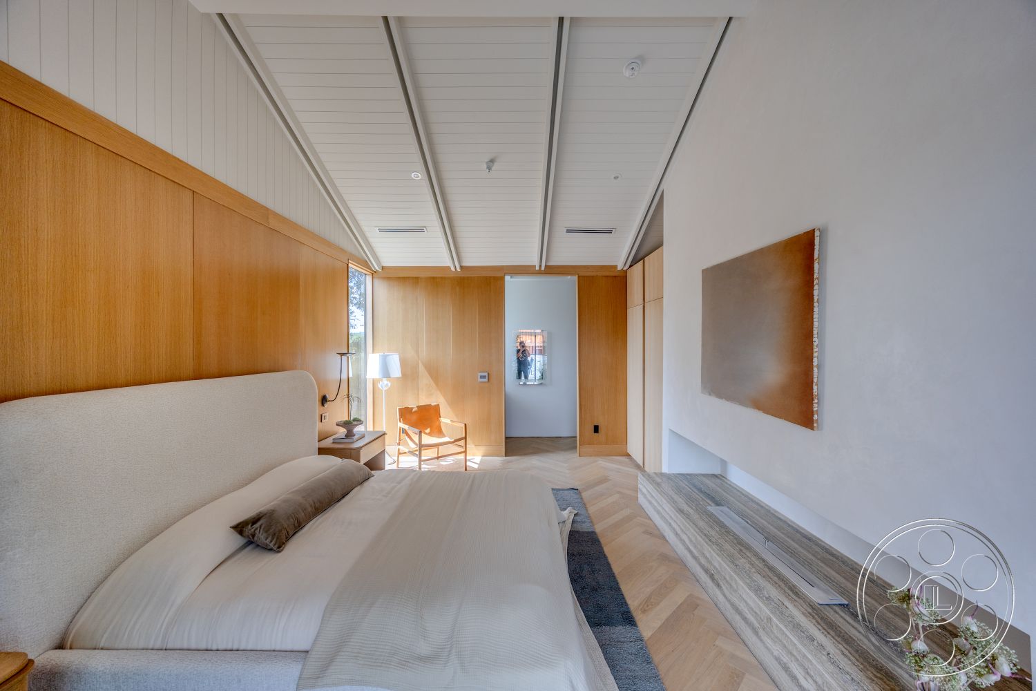 Modern 526 - decorative art piece, textured plaster wall, large window with natural light, white painted ceiling, wood panel accent wall, built-in wooden cabinetry, minimalist bedside lamp, chevron-patterned hardwood bedroom floors, upholstered bed frame, calm and modern bedroom setting