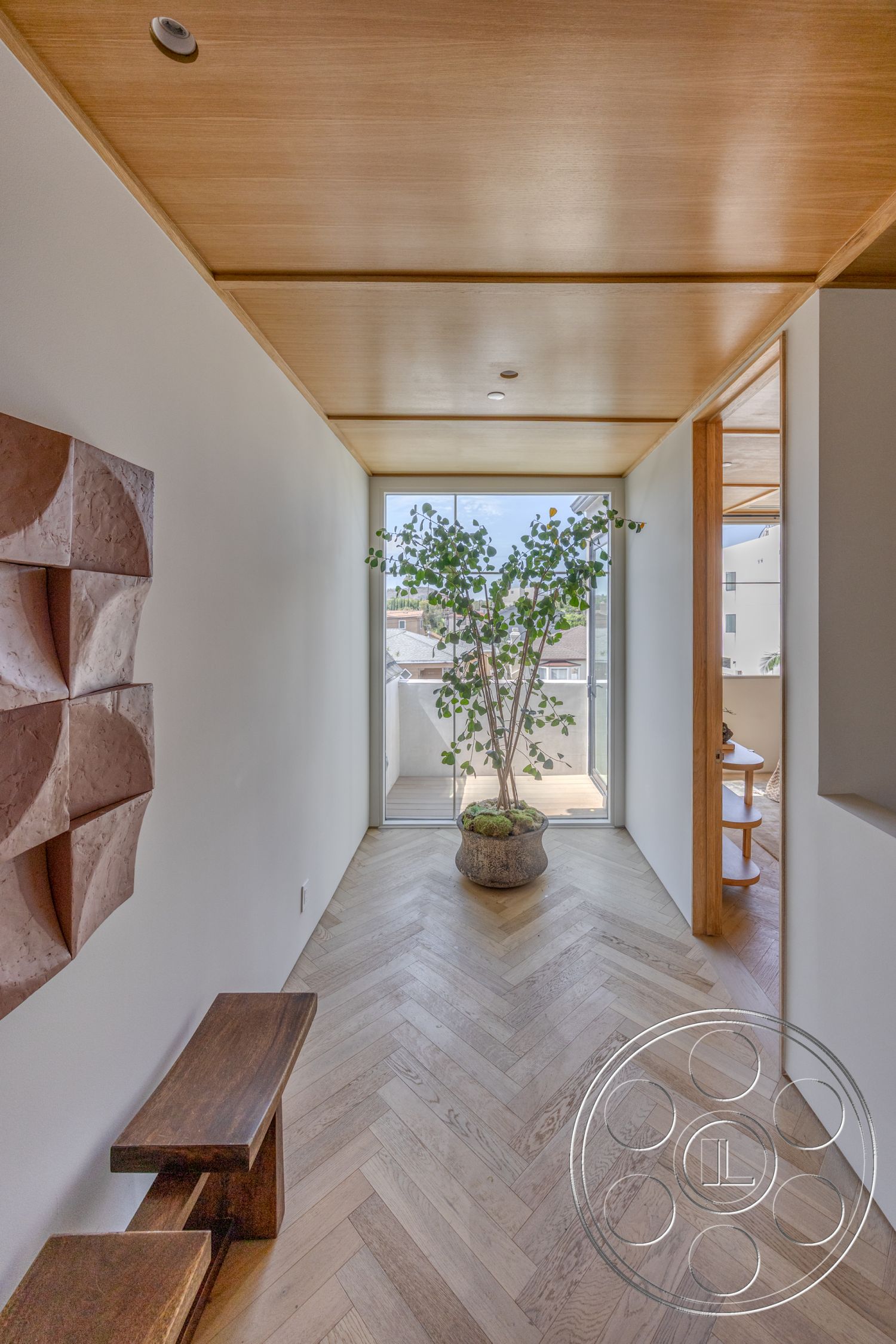 Modern 526 - wooden bench, glass sliding doors, wood beam ceiling, white painted walls, herringbone hardwood flooring, natural light-filled hallway, minimalist wall sculpture, indoor potted tree