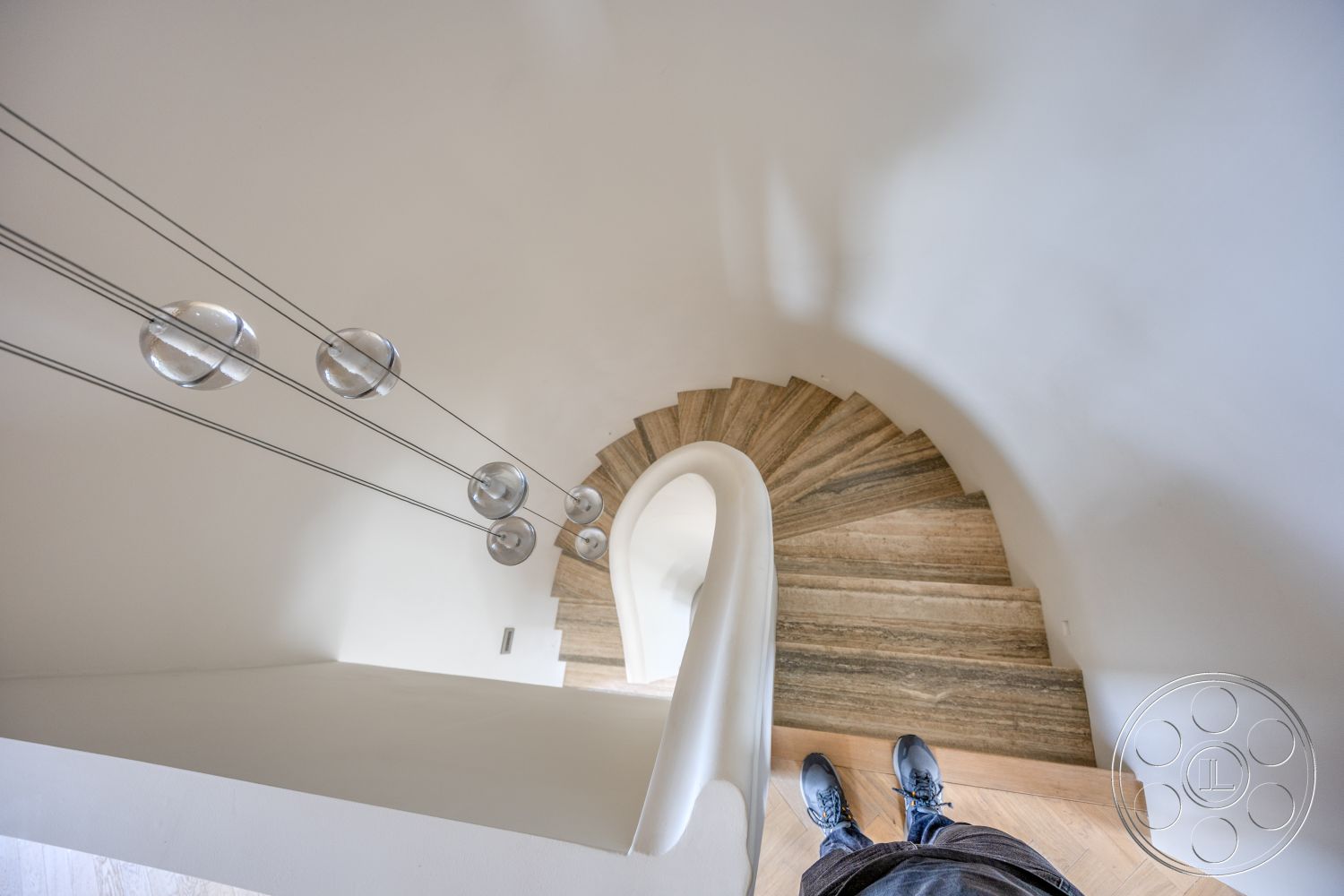 Modern 526 - white plaster walls, minimalist architectural style, herringbone hardwood flooring, open stairwell design, floating spiral staircase, wood steps with marble accents, modern pendant lighting with glass spheres, curved staircase handrail