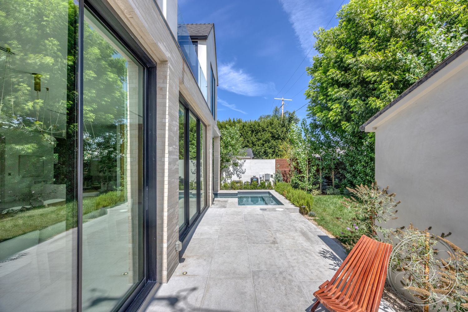 Modern 526 - exterior, glass sliding doors, greenery, rectangular swimming pool, modern architectural style, white brick walls, landscaped garden area, concrete patio flooring, hardwood patio bench