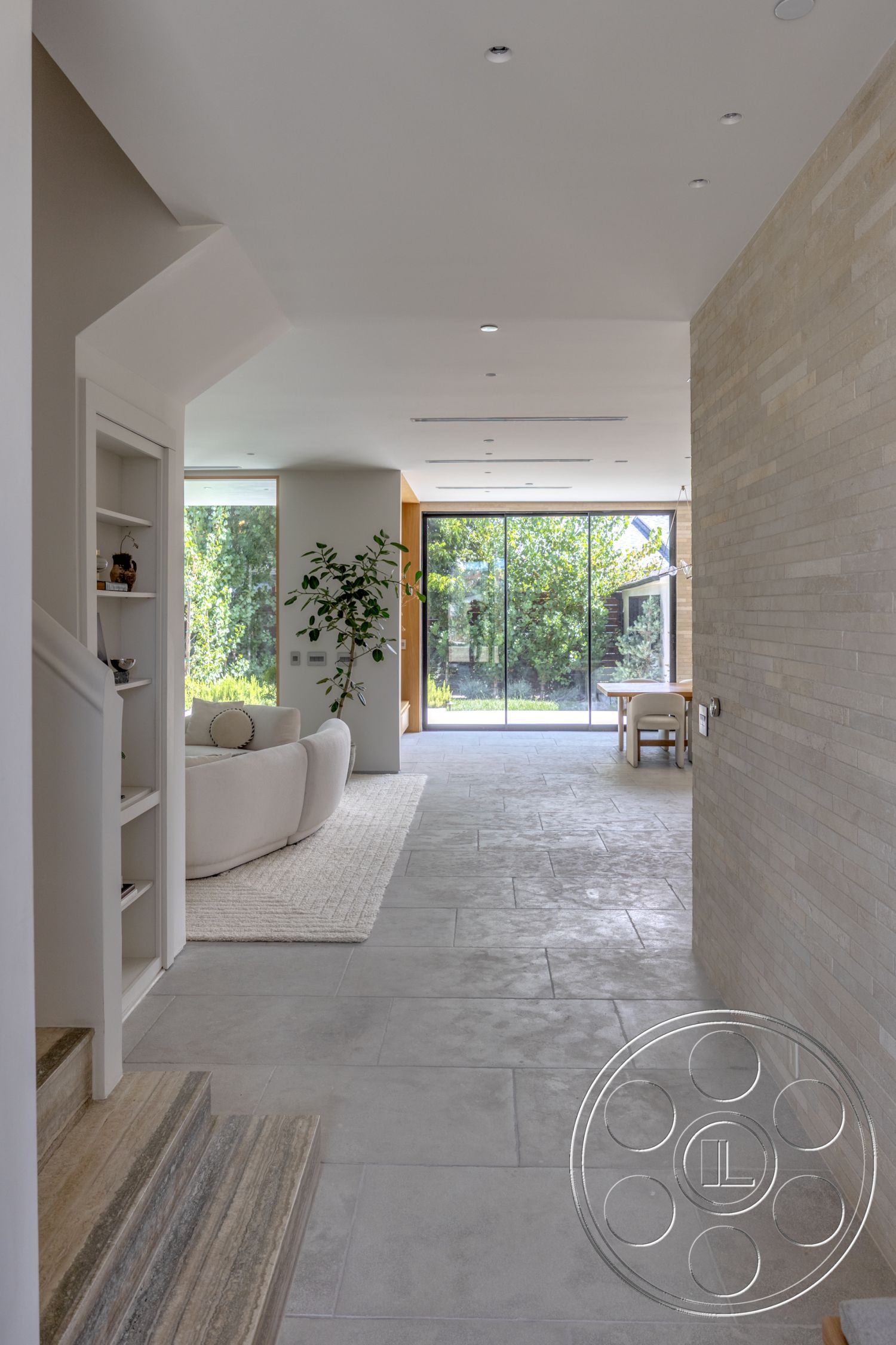 Modern 526 - neutral color palette, large glass sliding doors, open floor plan, exposed brick wall, curved sofa, stone tile flooring, modern minimalist design, natural light interior, white plaster ceiling, step-down entryway