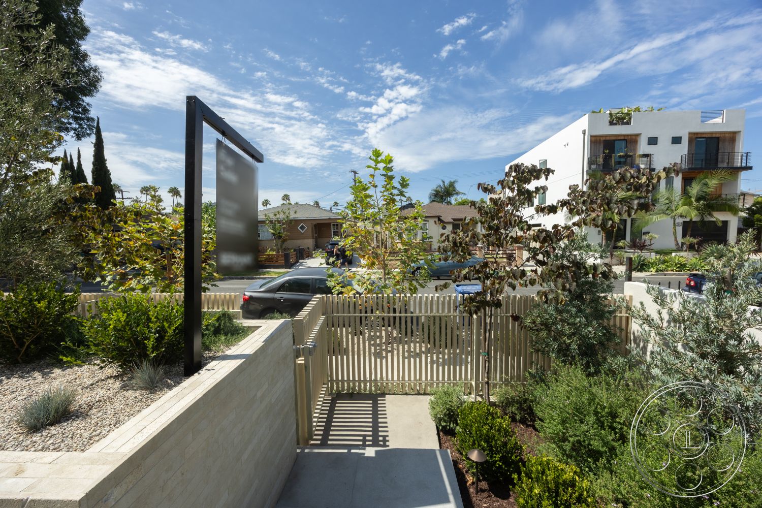 Modern 526 - exterior, paved driveway, concrete path, tropical landscaping, wooden fence, contemporary home design, landscaped garden with shrubs, decorative signage, modern architectural structure, textured paving stones