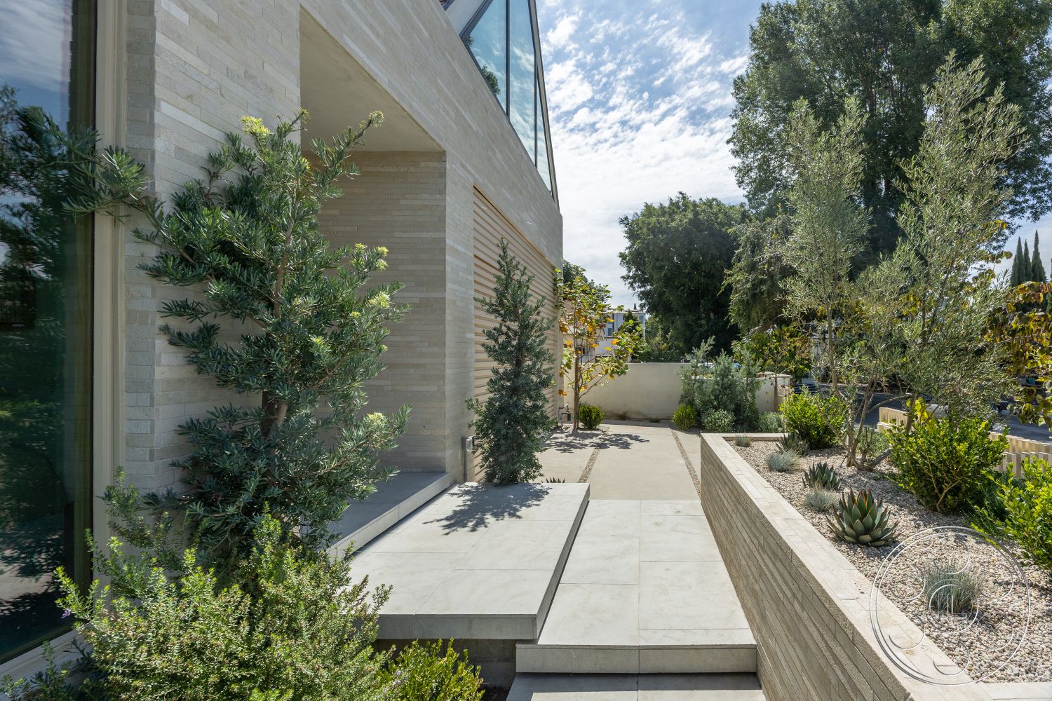 Modern 526 - exterior, floor-to-ceiling windows, modern architectural style, natural stone steps, concrete patio floor, landscaped garden with shrubs, horizontal wood slat wall, planted succulent garden, rectangular pathway, stacked stone feature wall