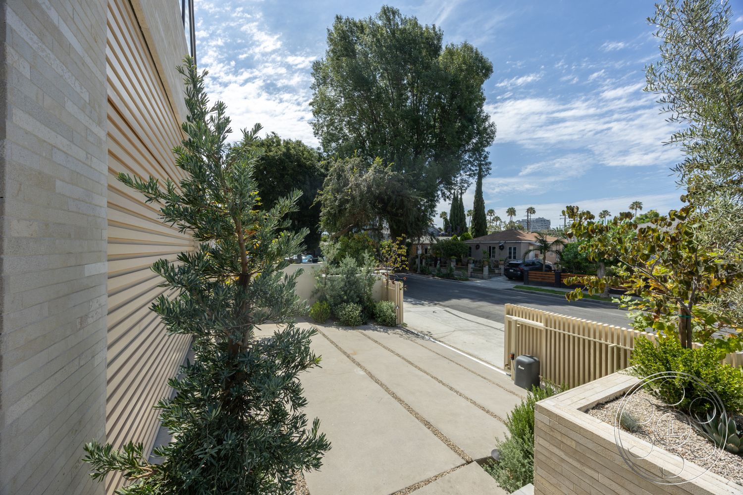 Modern 526 - exterior, palm trees, modern architectural style, concrete driveway, residential setting, decorative stone planters, landscaped garden beds, vertical wood slat siding, shrubbery and plants, open street view