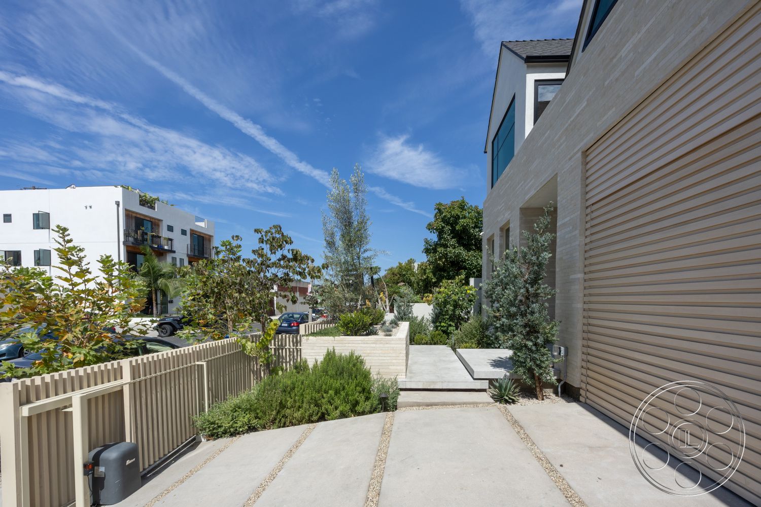 Modern 526 - exterior, low-maintenance landscaping, concrete steps, modern architectural style, concrete driveway, stone feature wall, planting beds with shrubs, horizontal wood fence, curved landscaping beds, clear blue sky setting, paved garden pathway