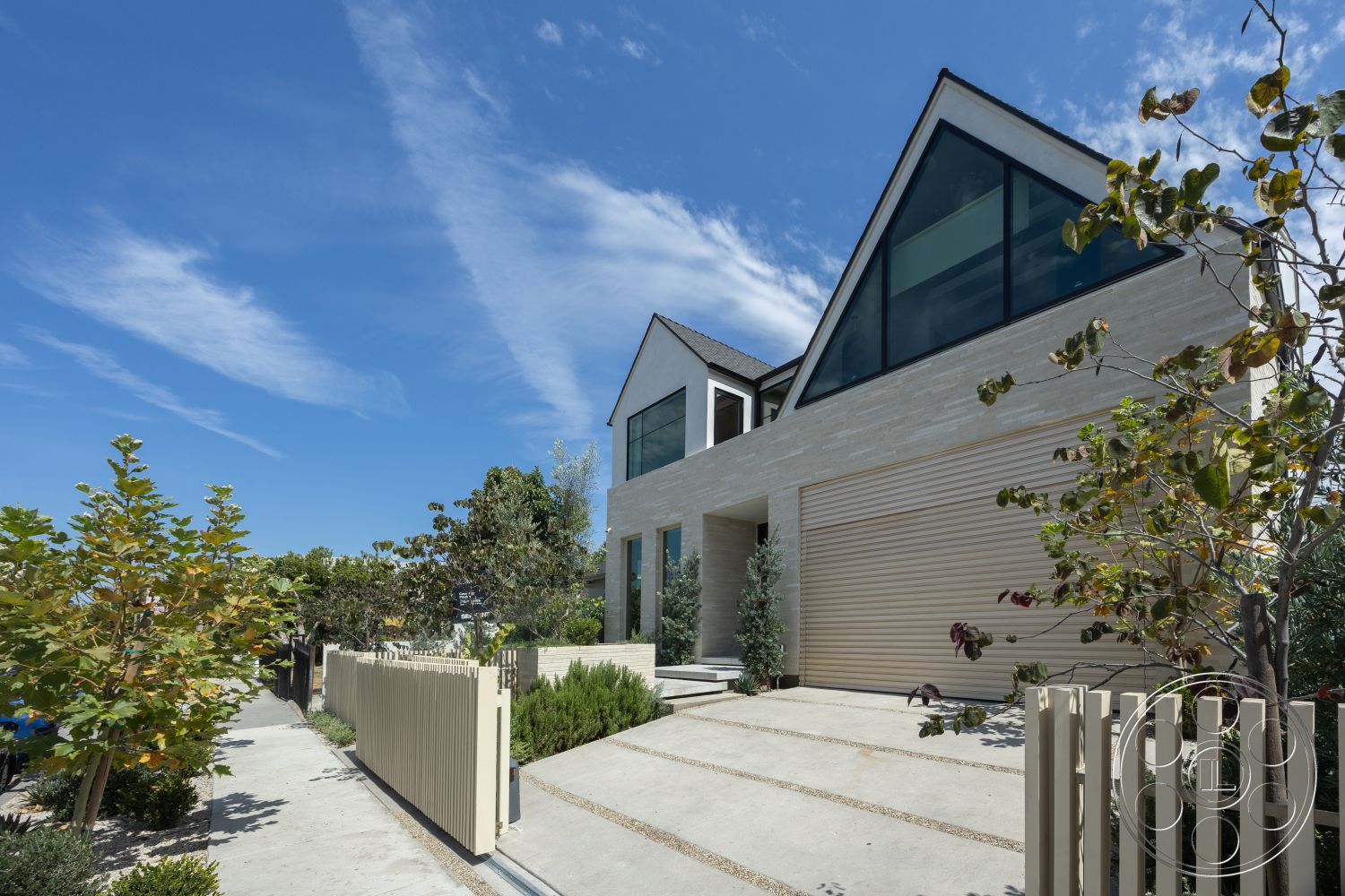Modern 526 - exterior, lush greenery, garage door, floor-to-ceiling windows, sloped roof, contemporary design elements, modern architectural style, gravel landscaping, concrete driveway, wooden fence, textured stone facade