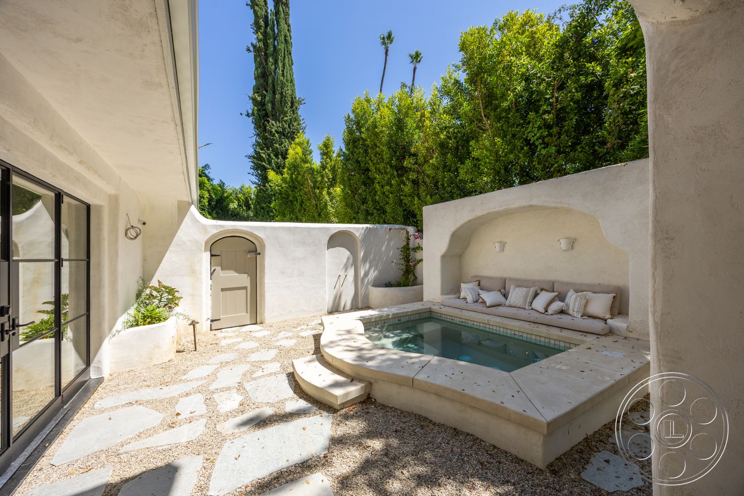 Medit 168 - exterior, textured wall finish, stucco walls, flagstone patio flooring, spa area with built-in seating, octagonal pool shape, landscaped garden with privacy, arched wall niches with lighting, gray stone pathways, metal door with neutral finish