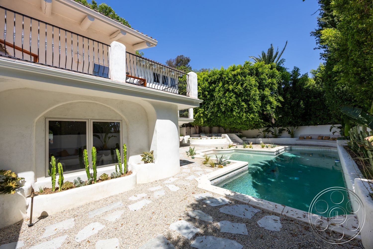 Medit 168 - exterior, flat roof, rectangular swimming pool, stone pathway, plaster walls, paved outdoor area, poolside lounge area, stone pool deck, large sliding glass windows, landscaped garden with succulents, railings with vertical metal slats, wooden balcony, tropical greenery setting