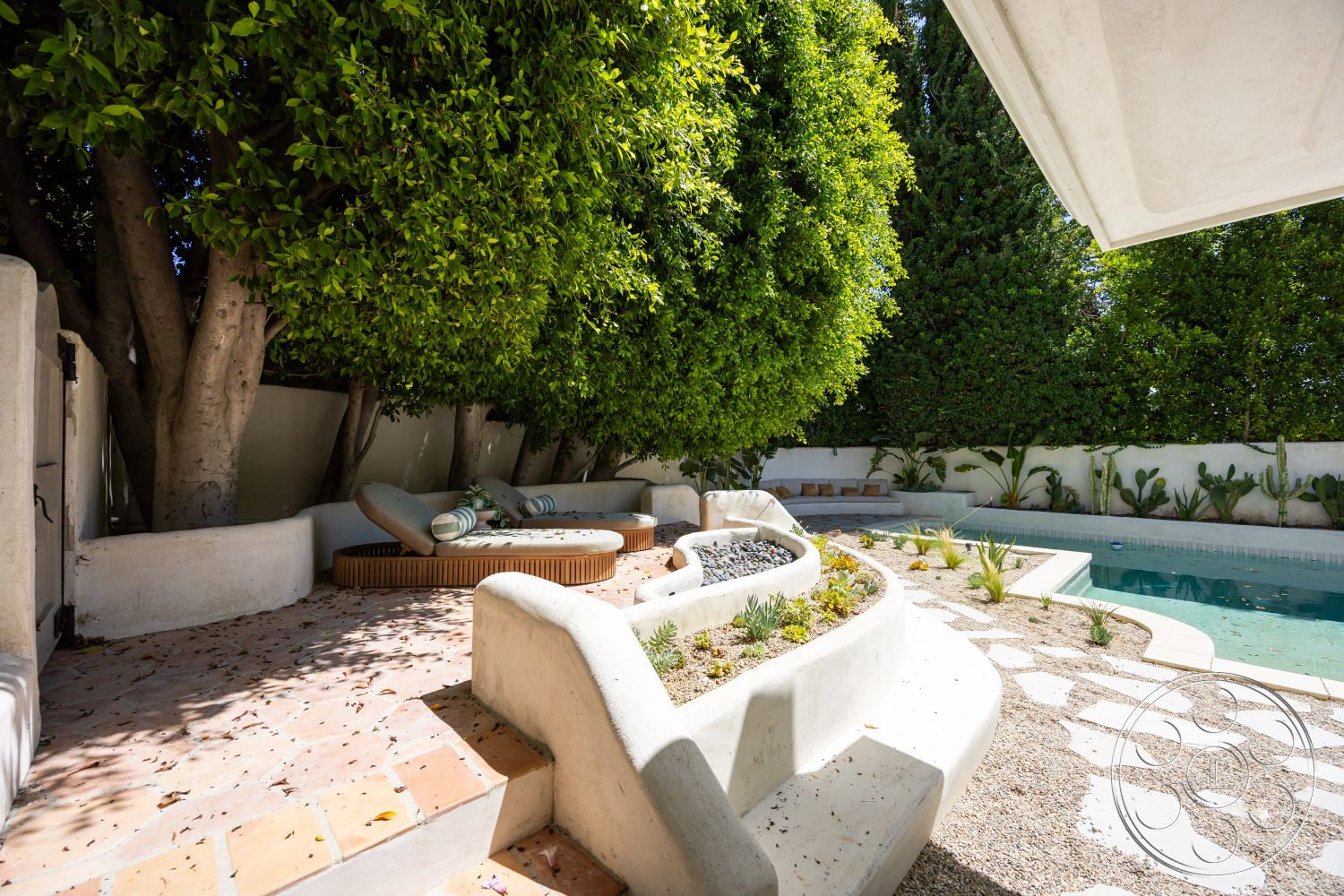 Medit 168 - exterior, white stucco walls, rectangular swimming pool, concrete seating area, drought-tolerant landscaping, landscaped garden bed, curved concrete steps, natural stone patio flooring, lush greenery landscaping, wooden lounge furniture, modern outdoor design, tropical plant features, paver pathways