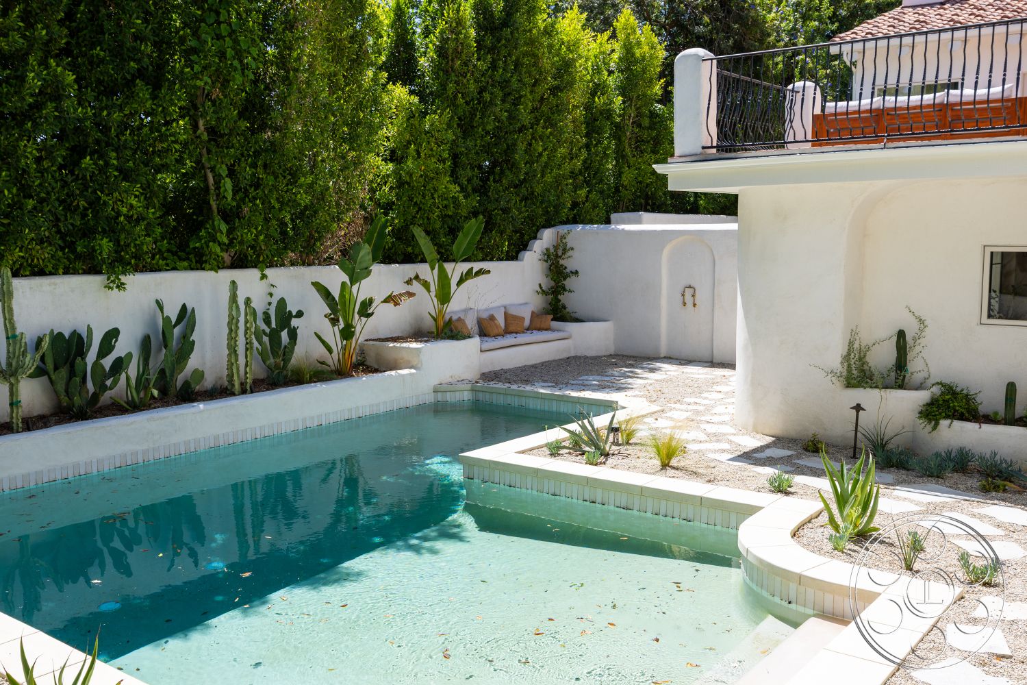 Medit 168 - exterior, white stucco walls, lush green hedges, rectangular pool, landscaped garden area, stone patio flooring, concrete pool border, minimalist outdoor seating, metal balcony railing, terracotta tiled roof, potted cacti and succulents, textured stone wall features